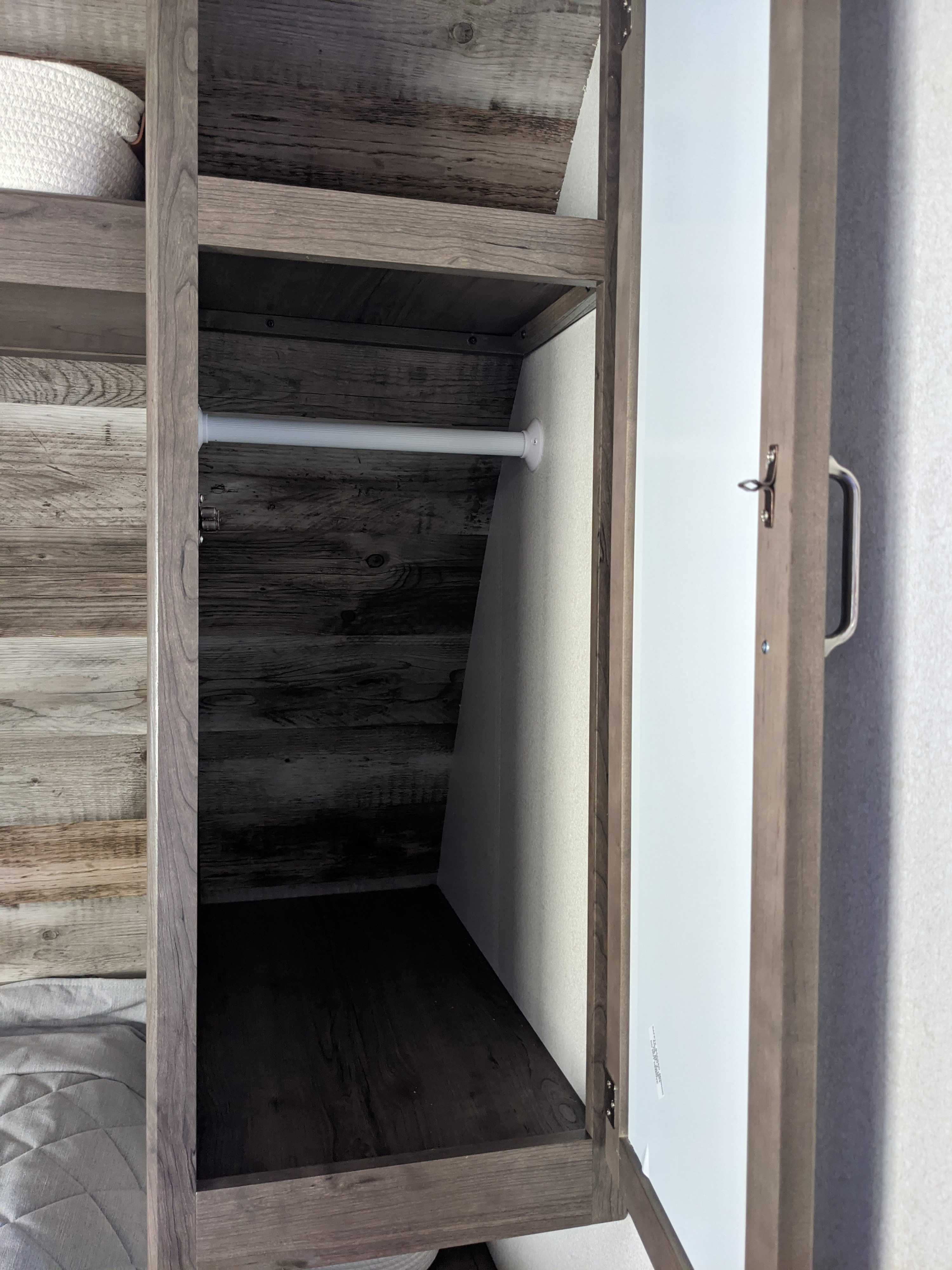 RV rental closet with hanging rod and storage. This open wardrobe has a shelf and wood-look interior for camper organization.. Other Other 2021