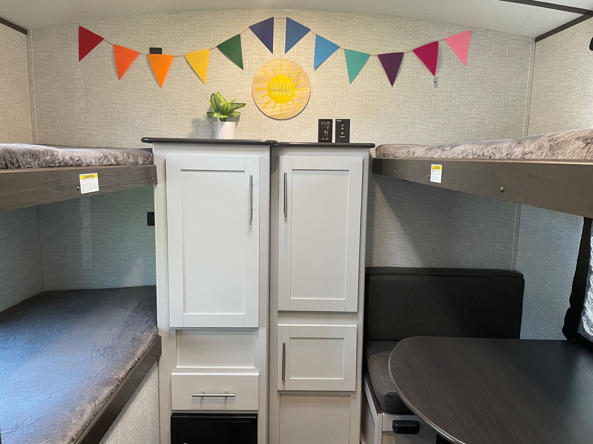Cozy RV rental interior featuring bunk beds, central storage cabinets, a dinette, and colorful decor.. Keystone Bullet Ultra Lite 2021