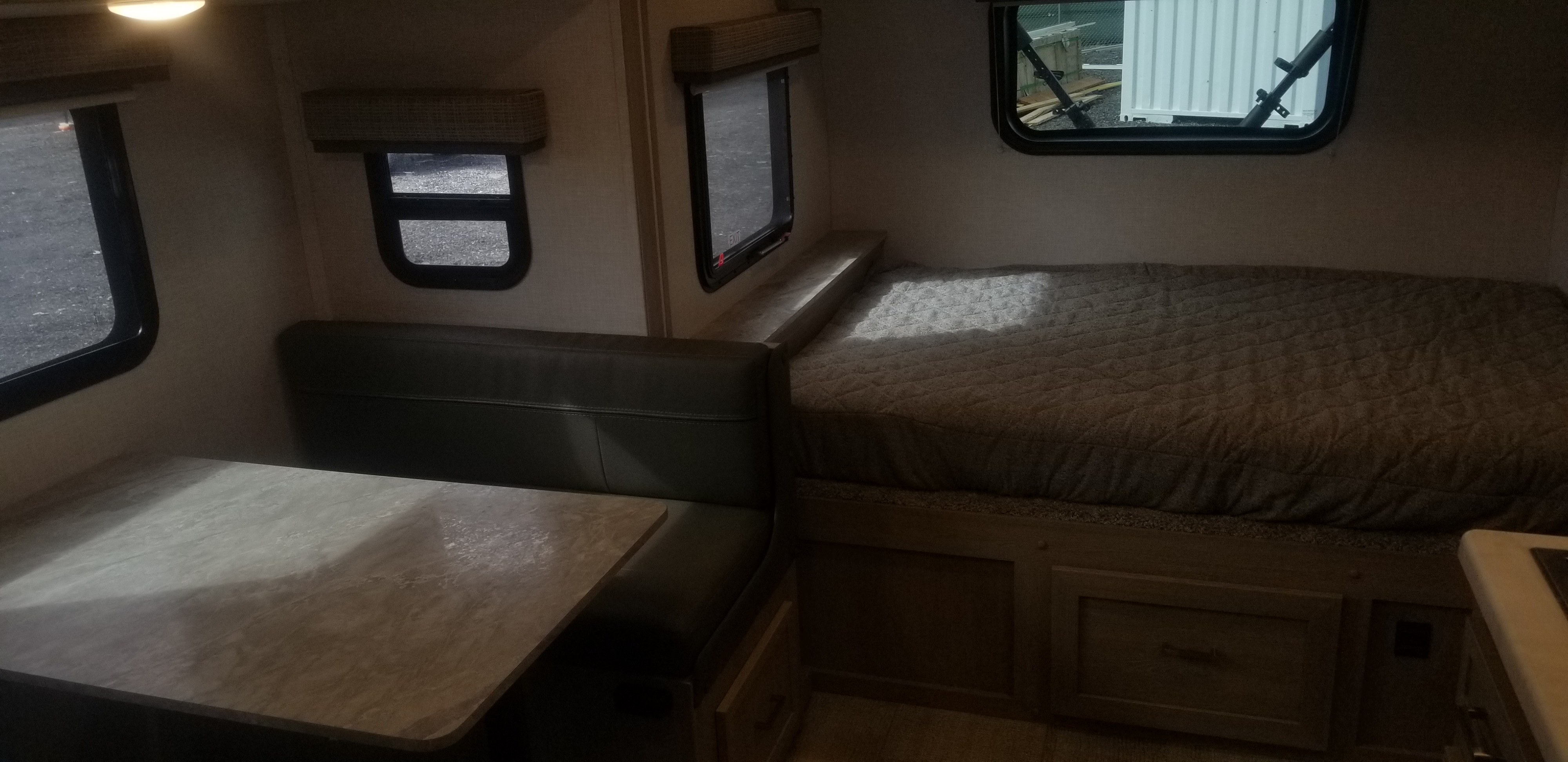 Inside this RV rental: a comfortable dinette with a table and bench seating on the left, next to a cozy bed on the right with storage below.. Forest River Flagstaff 2021