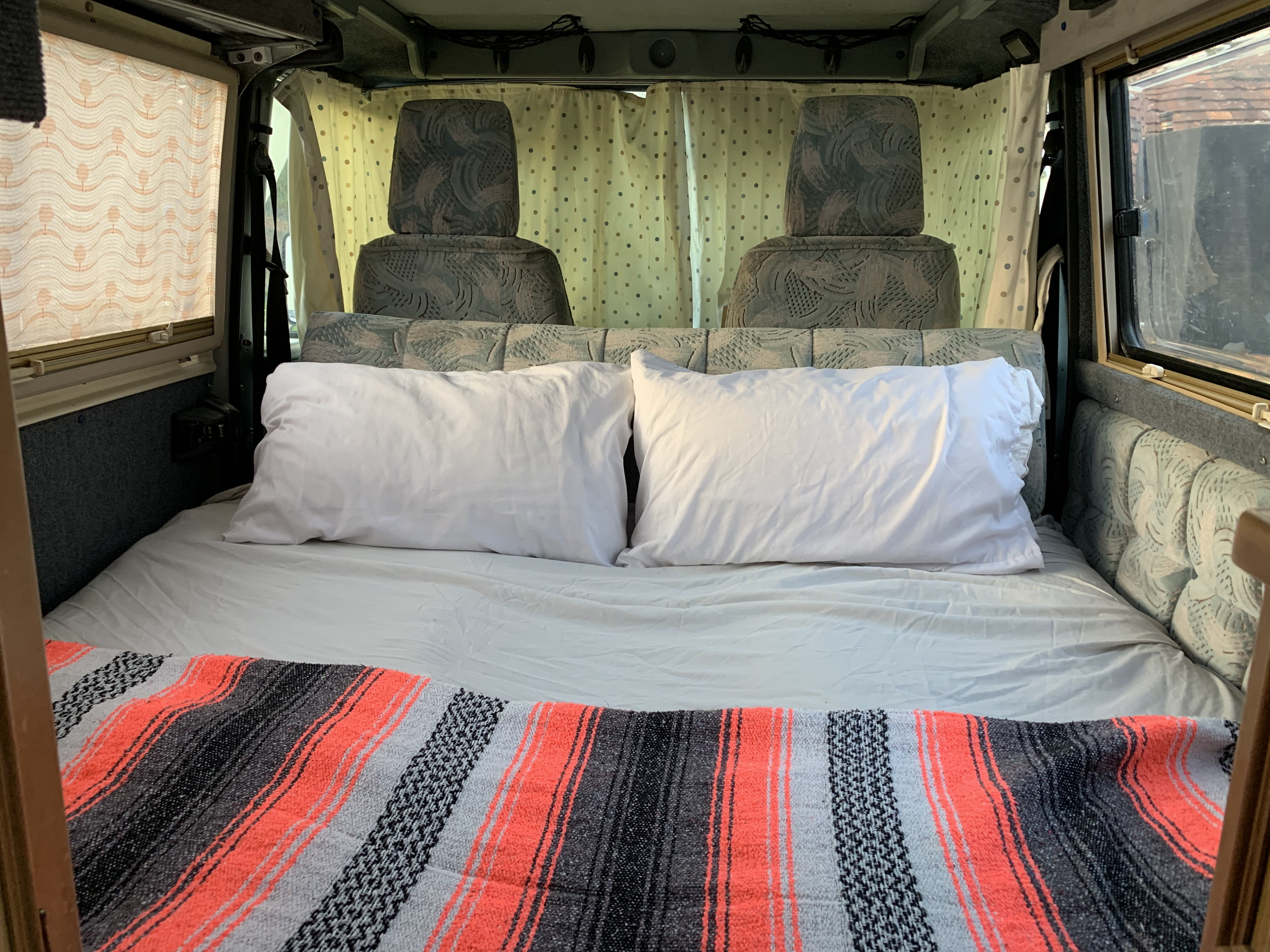 Relax in this RV rental's cozy bed! White pillows, striped blanket, & polka dot curtains create a comfy sleeping space.. Other Other 1994