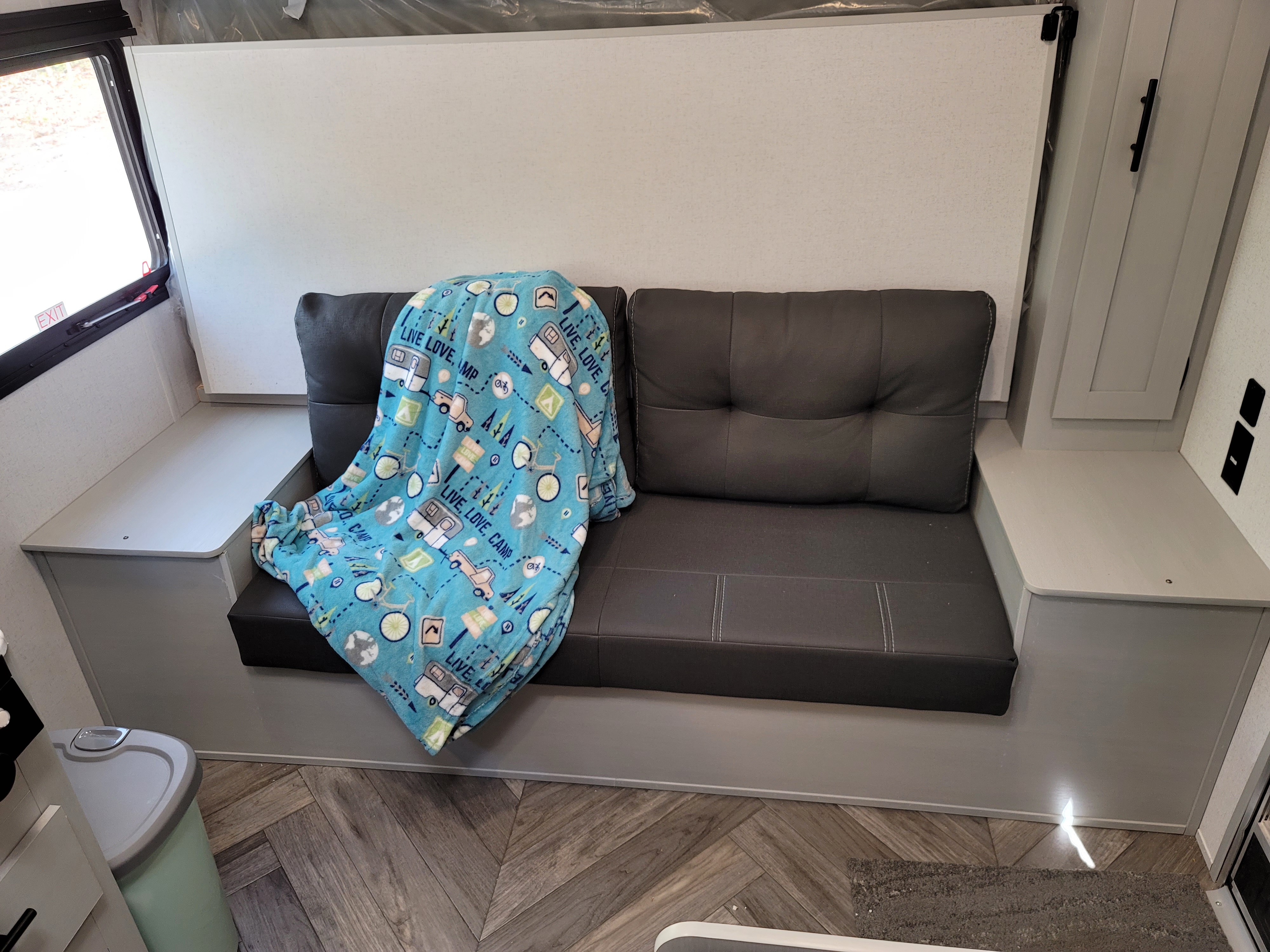 RV rental seating area with a cozy camping blanket, emergency exit window, and built-in storage. Ideal for road trips.. Forest River Salem 2021