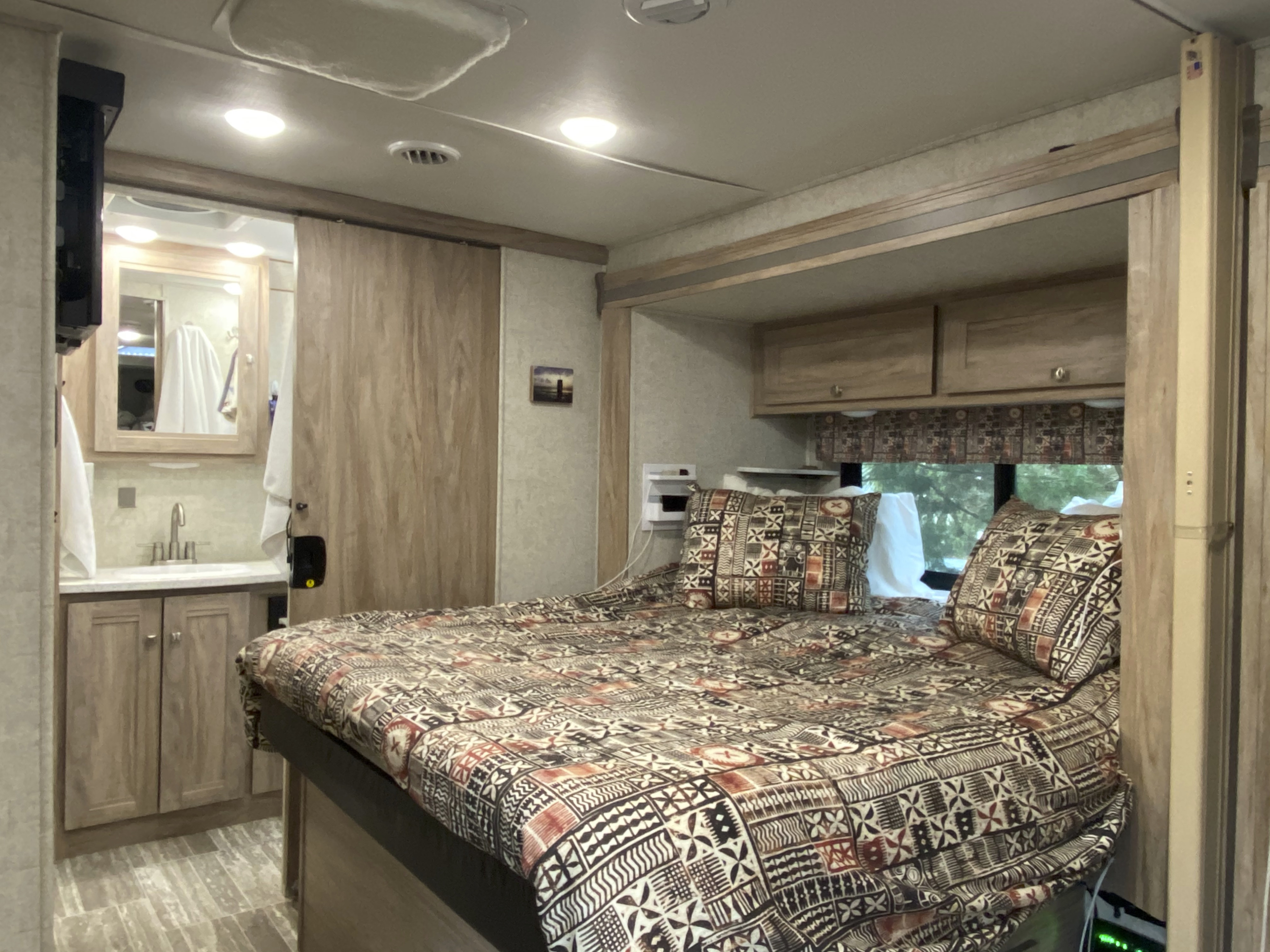 Enjoy the amazingly comfy queen bed with soft clean white, sheets four pillows and tiki inspired bedding and valance. . Forest River Forester 2020