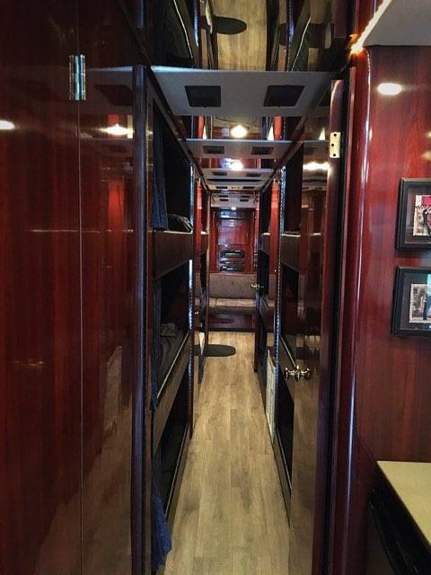 RV rental interior: Long hallway with reflective ceiling, dark wood panels & bunk beds on both sides for multiple sleepers.. Prevost Le Mirage 2003