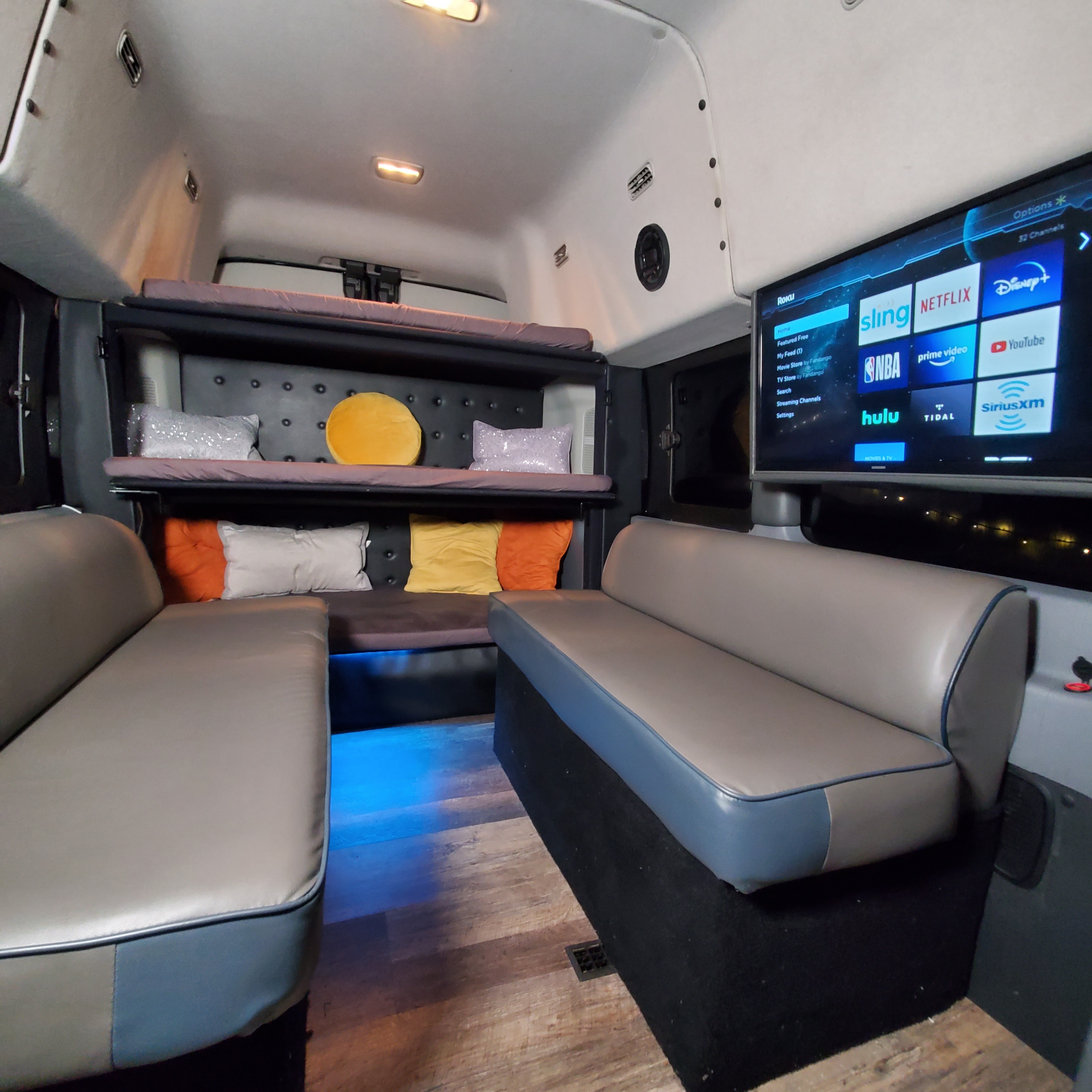 Inside an RV rental: plush seating, bunk beds, and a TV with streaming apps like Netflix and Hulu for your journey.. Ford Custom Transit 2017