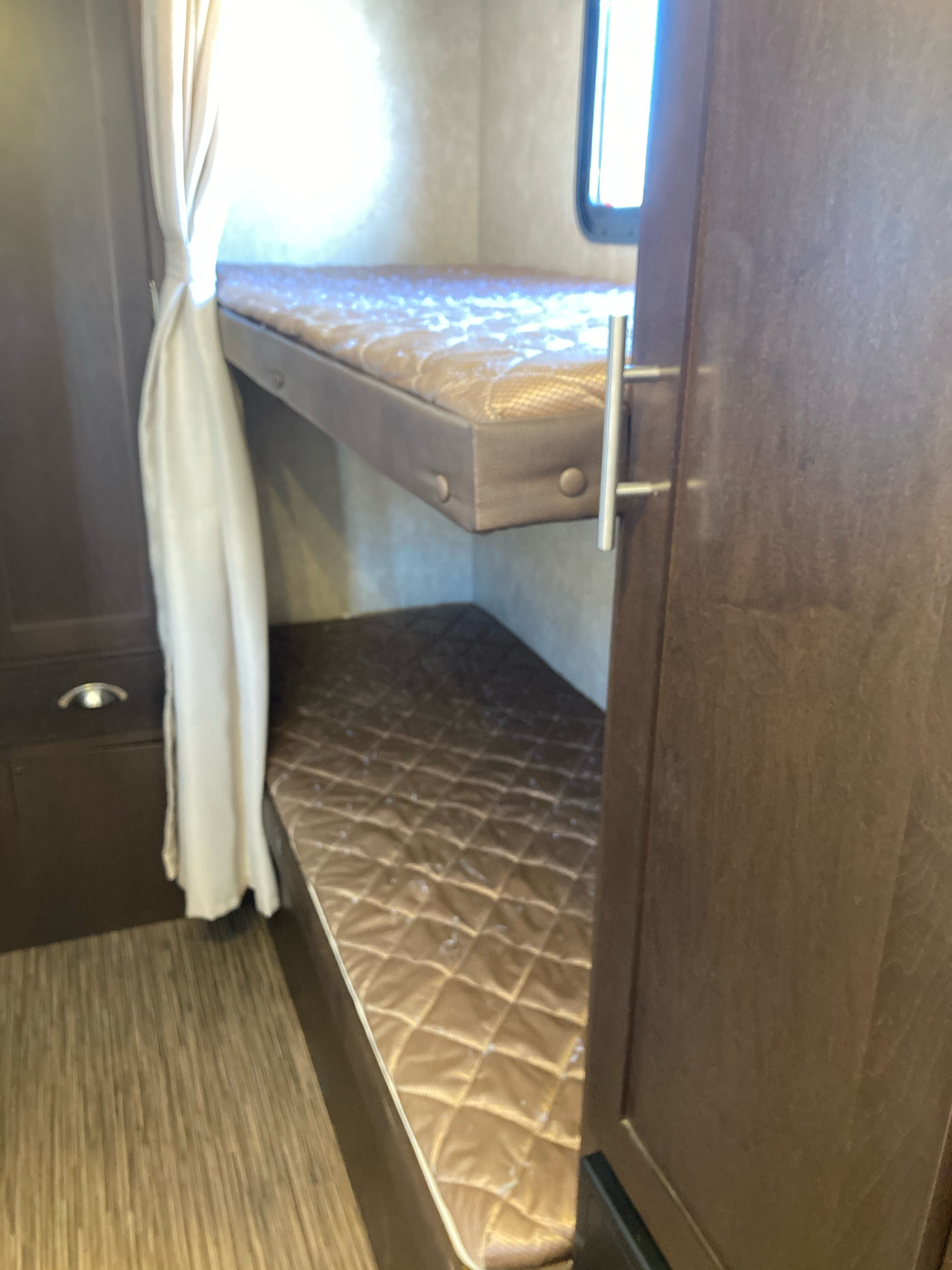 This RV rental shows a cozy bunk bed area with two quilted mattresses, a window, and built-in storage, great for camping.. Forest River Evo 2016