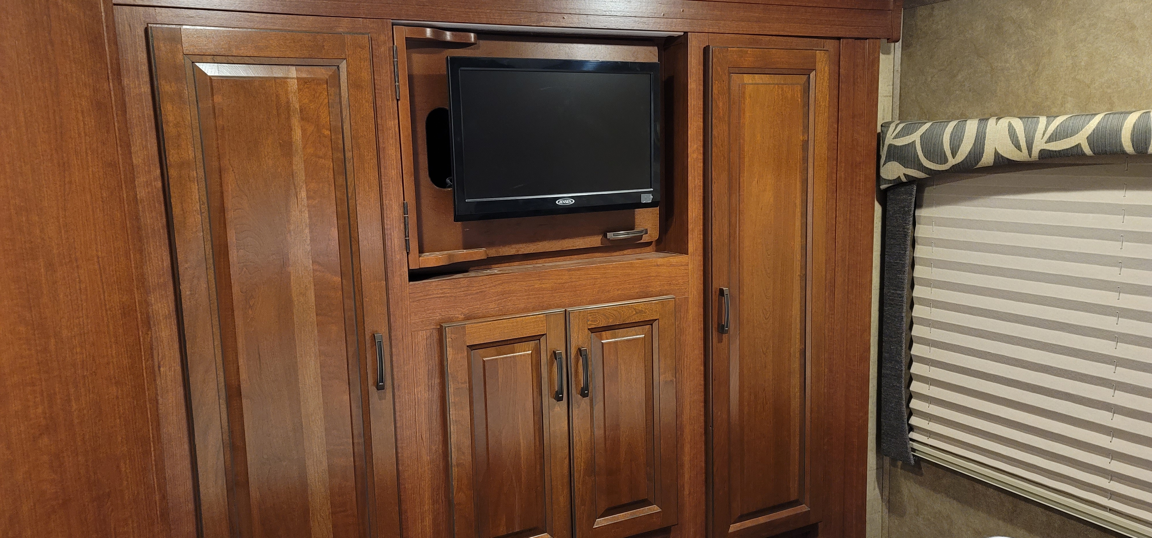 Built-in TV, dark wood cabinets, and window blinds outfit this RV rental's living space.. Forest River Other 2015