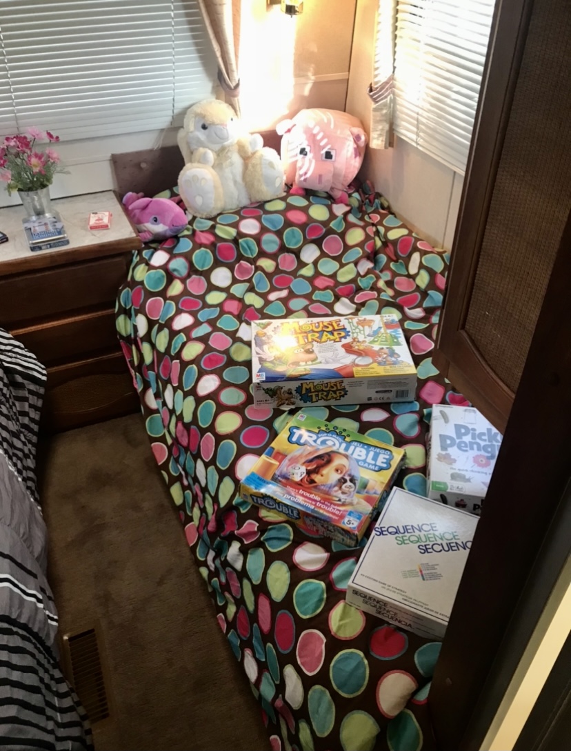 Cozy RV rental bunk bed with plush toys and board games (Mouse Trap, Trouble) on a colorful polka dot comforter.. Ford Econoline 1988