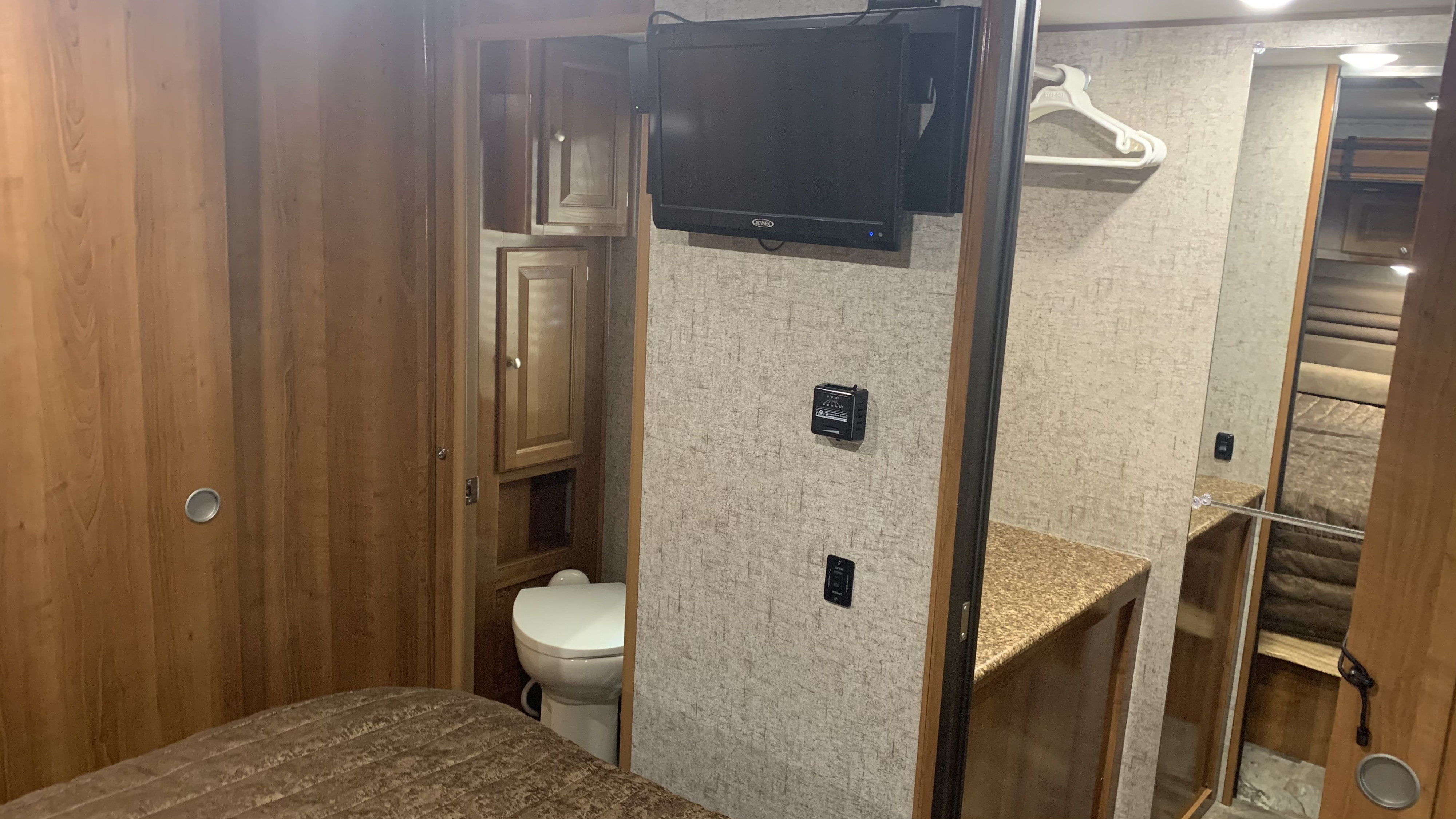 RV rental interior: bedroom features a TV, bed, closet, and compact bathroom with toilet & cabinets. Ideal for travel.. Other Other 2018