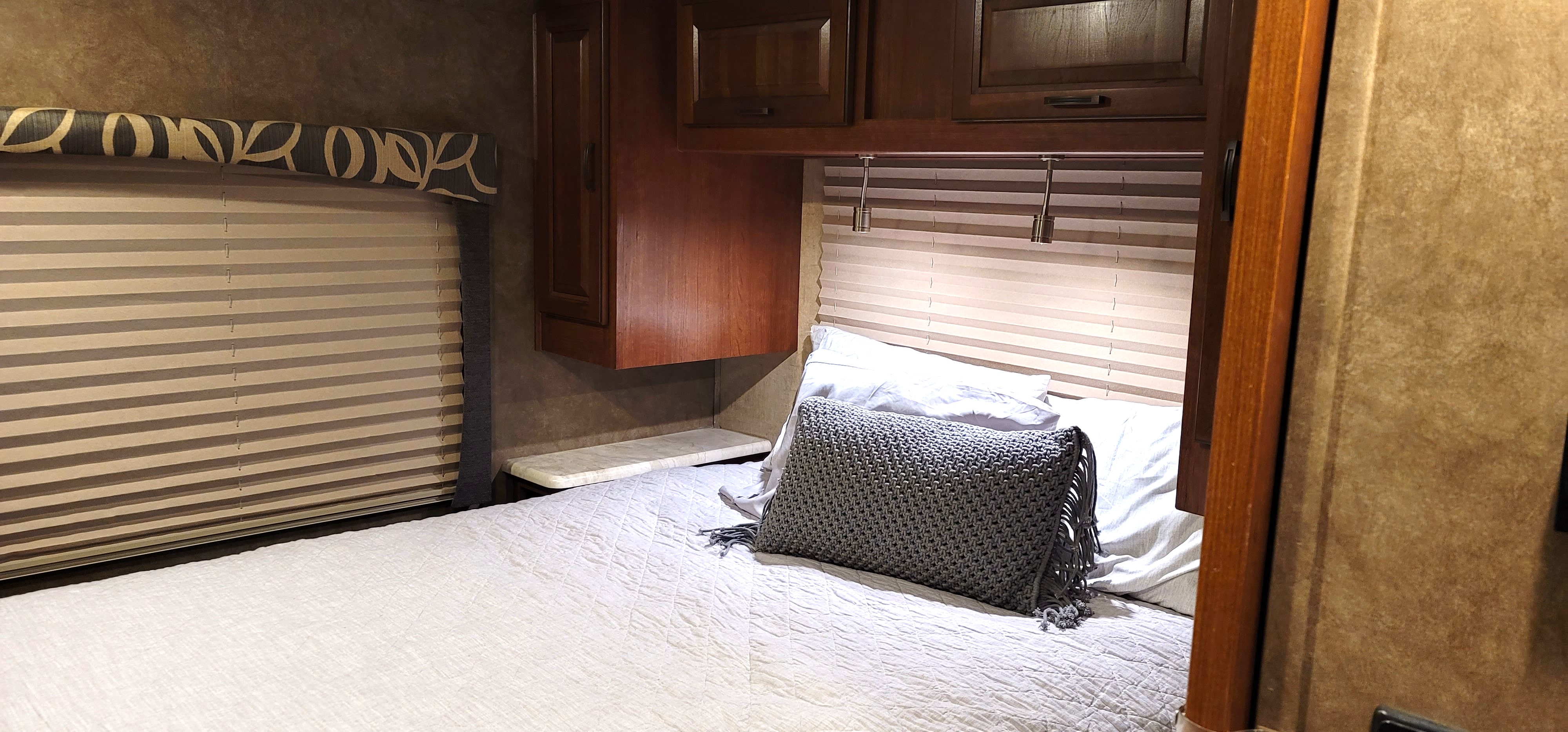 Inside an RV rental: a comfy bedroom with storage cabinets, window blinds, and reading lights over the bed.. Forest River Other 2015