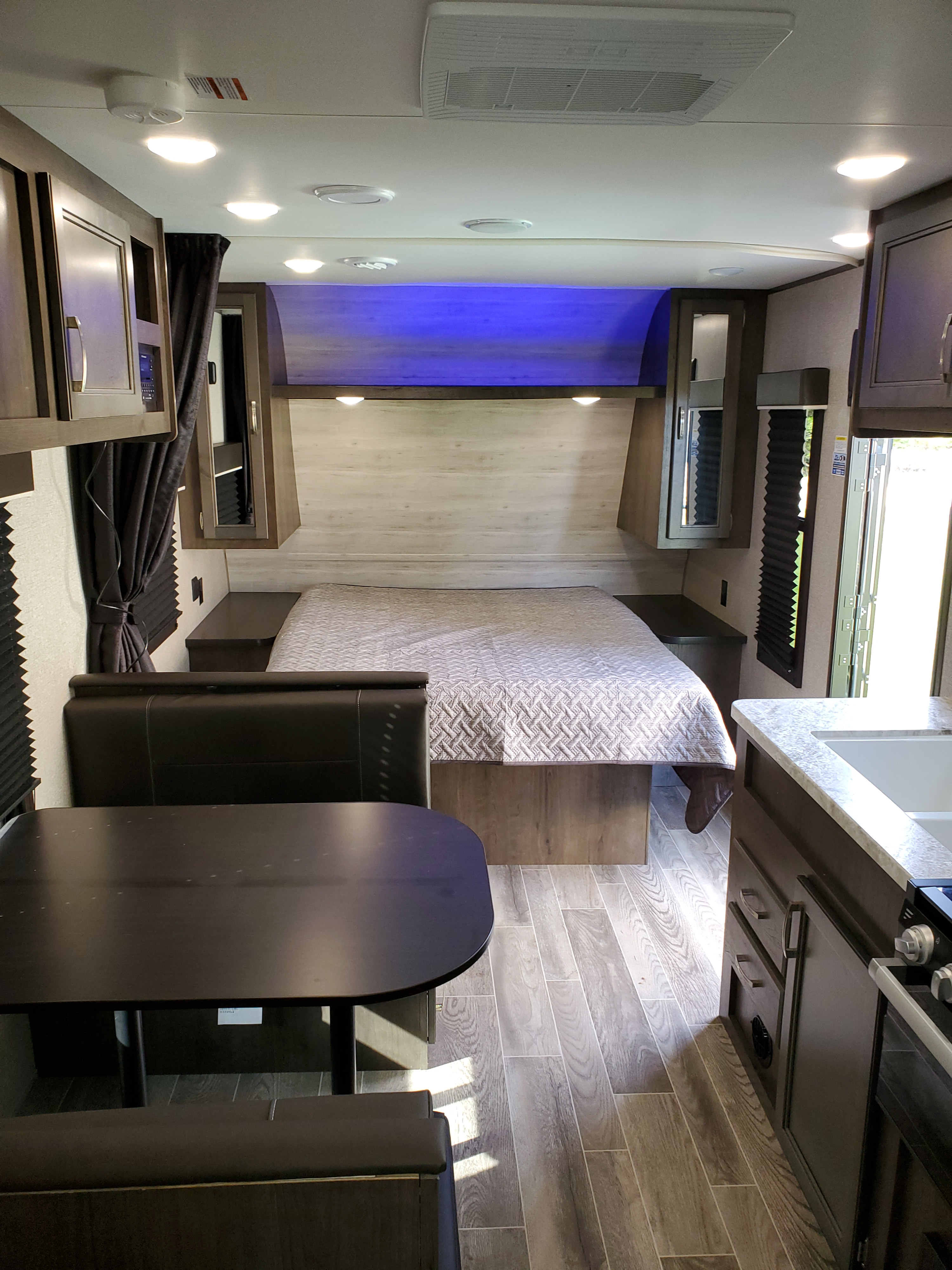 Well-appointed RV rental interior with dining booth, kitchen, bed, overhead AC, and wood-look flooring.. Jayco Jay Flight 2021