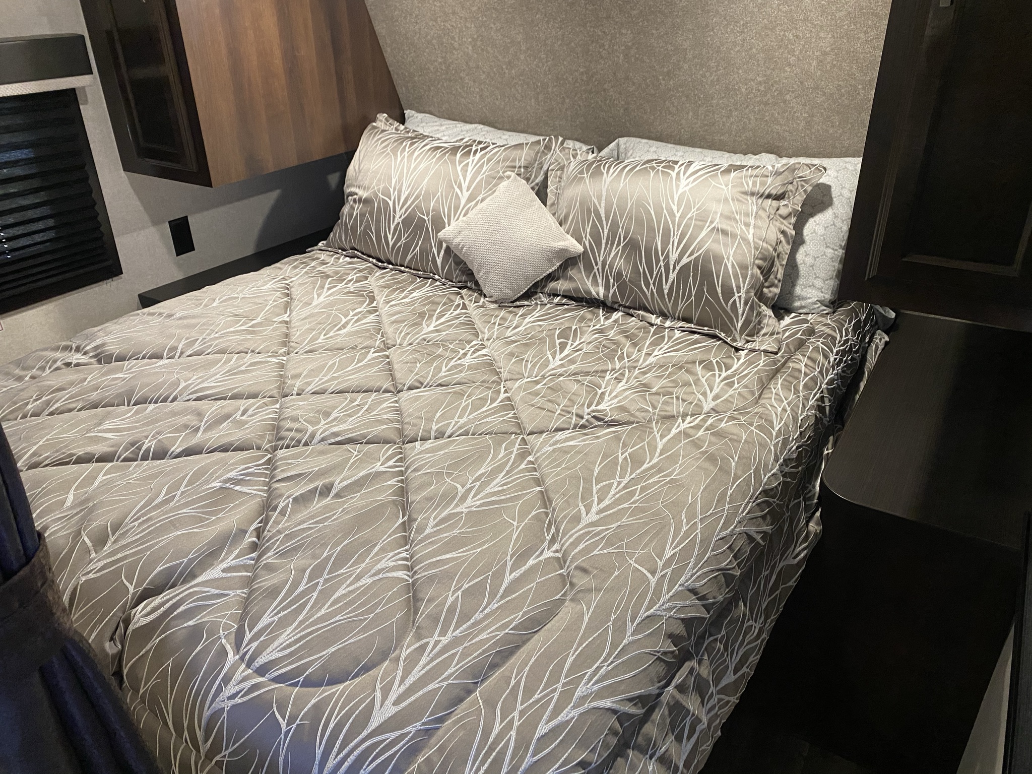 Cozy RV rental bedroom with a comfortable bed, featuring a unique branch pattern comforter and pillows. Ready for your adventure!. Jayco Jay Flight 2021