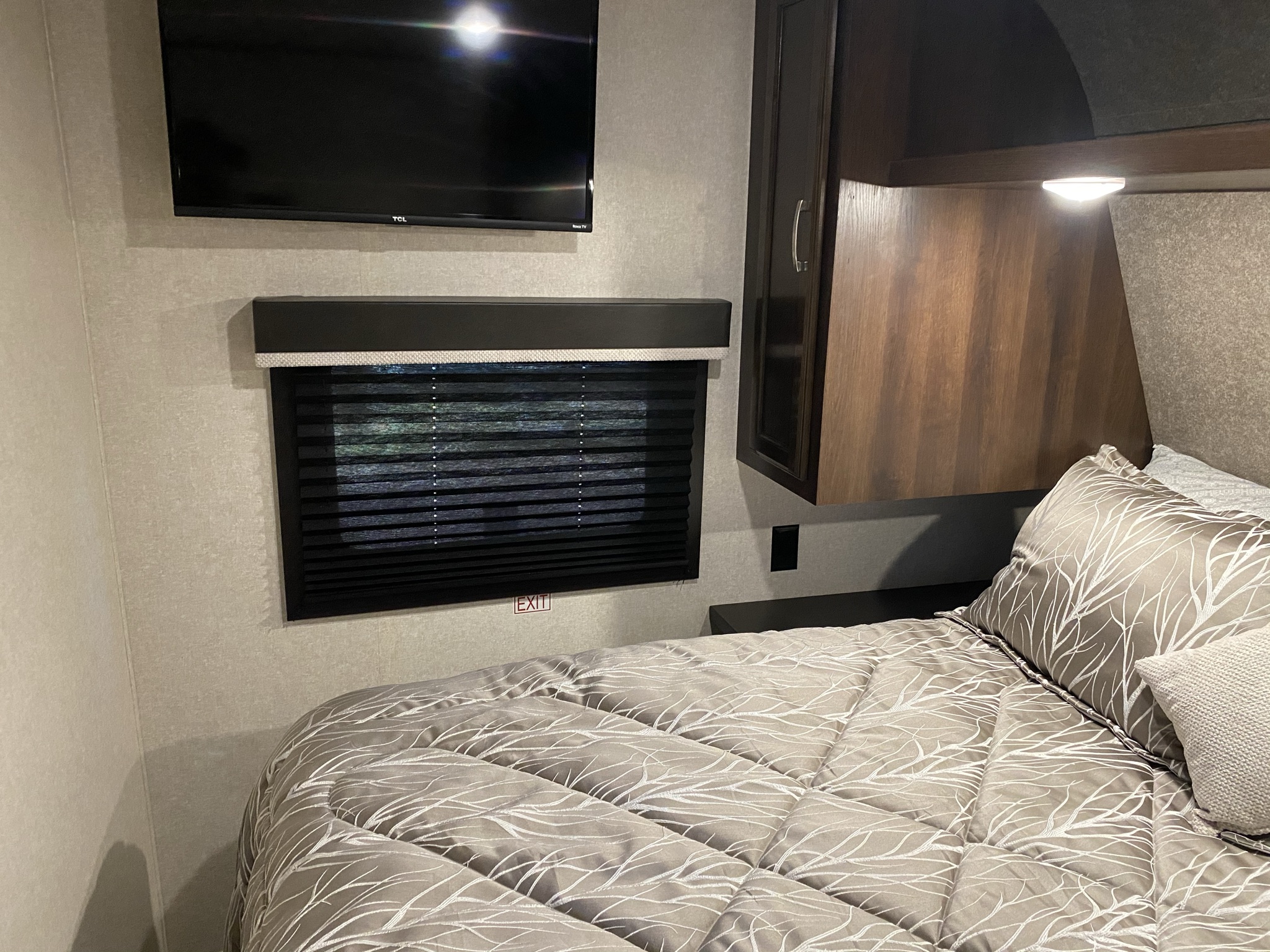 RV rental bedroom interior: bed with patterned comforter, wall TV, window with blinds, and EXIT sign. Great for travel.. Jayco Jay Flight 2021