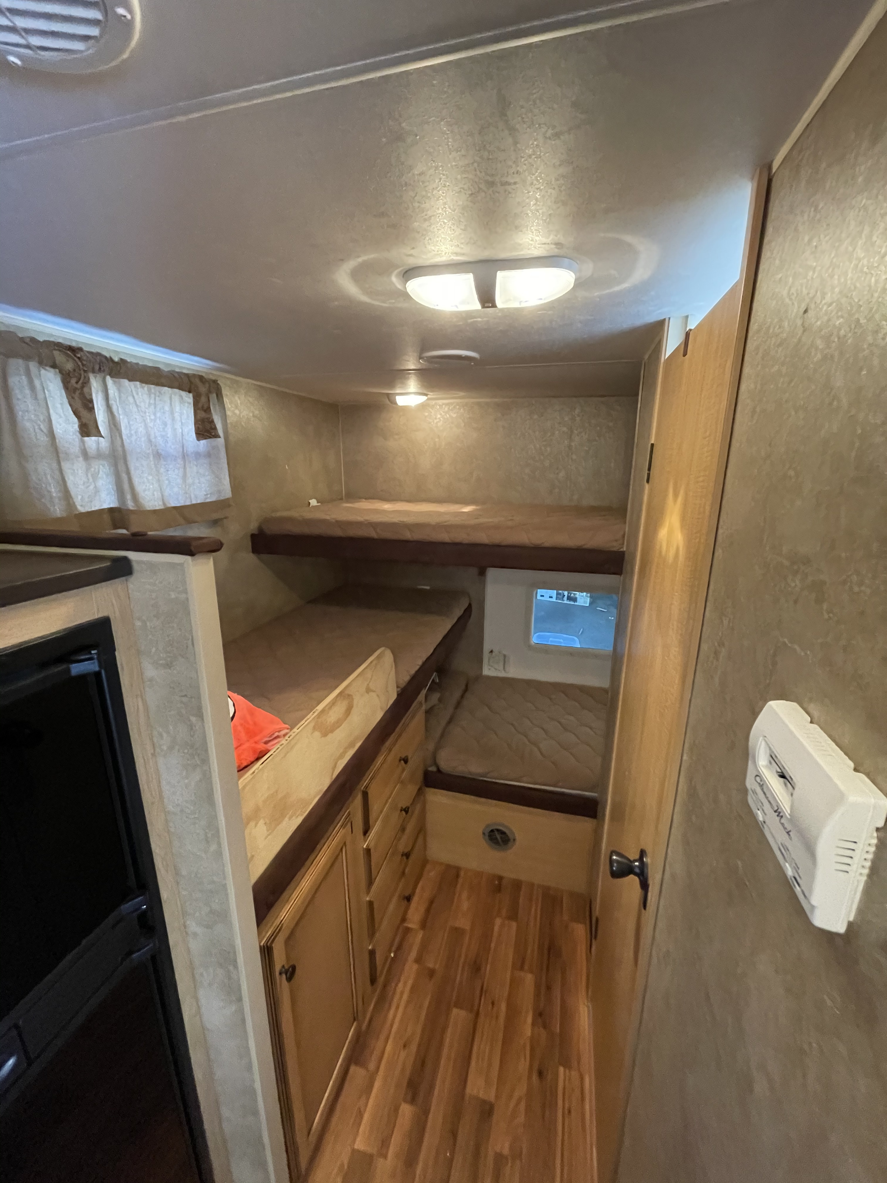 RV rental: compact bunk room with two beds, wood flooring, a window, and adjacent kitchen cabinetry.. K-Z Manufacturing Spree Ultra-Lite 2012