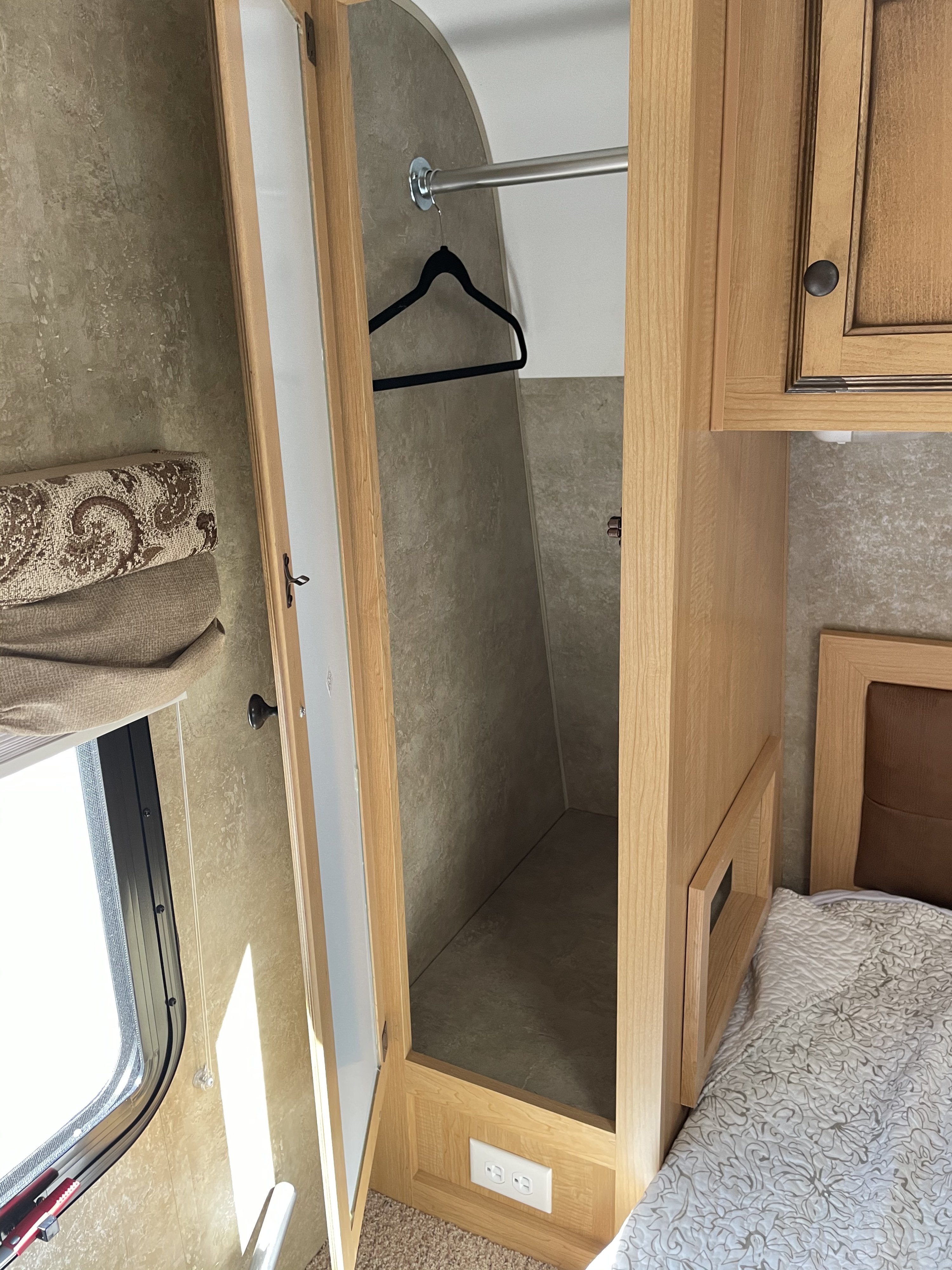 RV rental bedroom with open wood closet, hanging rod, and bed. Practical, compact living space on wheels.. K-Z Manufacturing Spree Ultra-Lite 2012