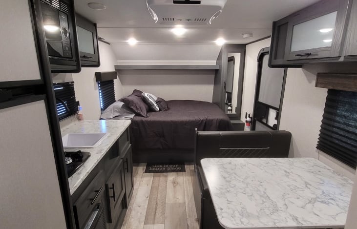 Spacious, modern RV rental interior featuring a kitchen, comfortable bed, and dinette area for travel.. Dutchmen ASPEN TRAIL 1950BH 2021