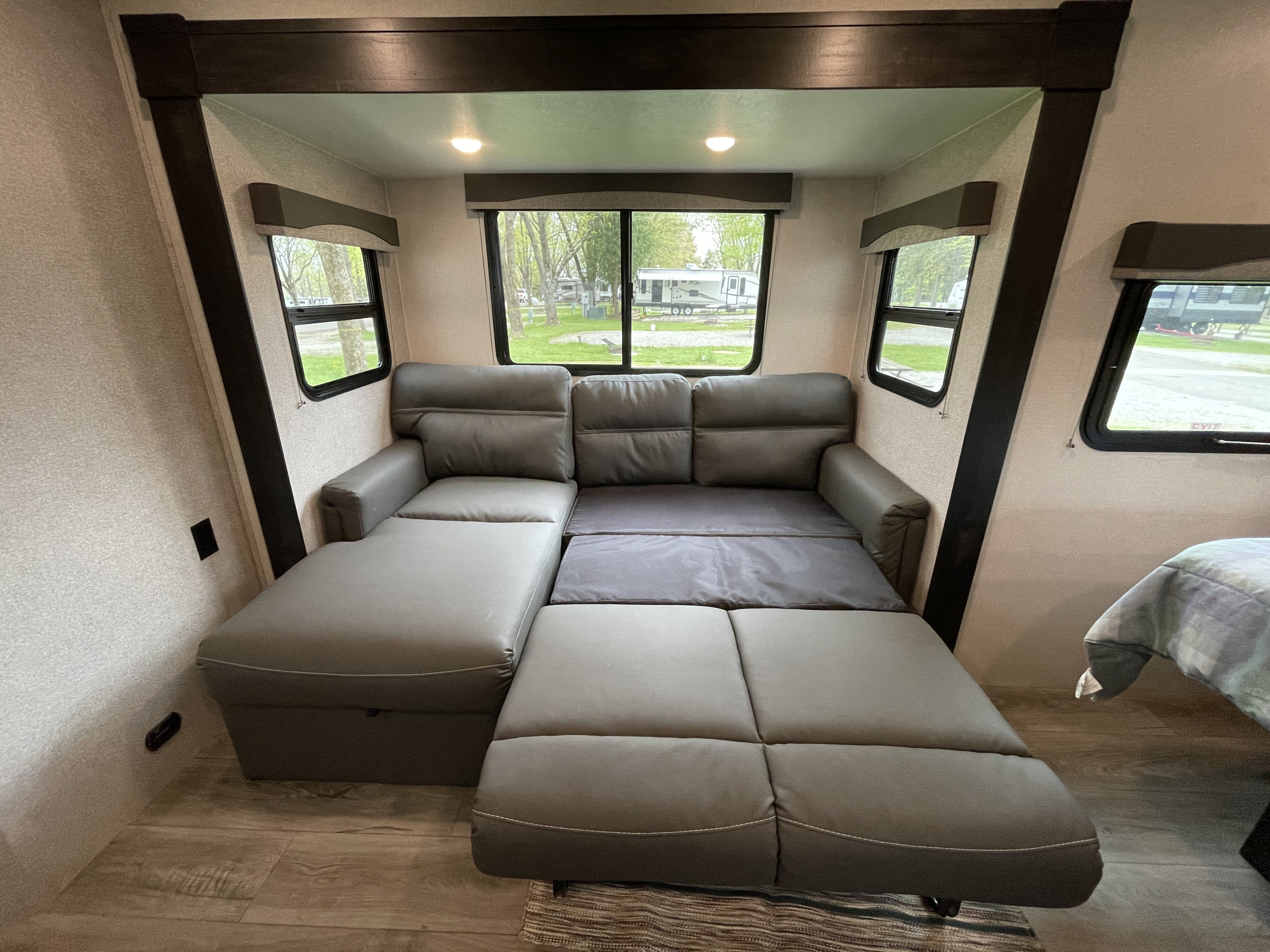 Spacious RV rental interior featuring a versatile gray sectional sofa that converts into a bed, with large windows.. Starcraft Super Lite 2021