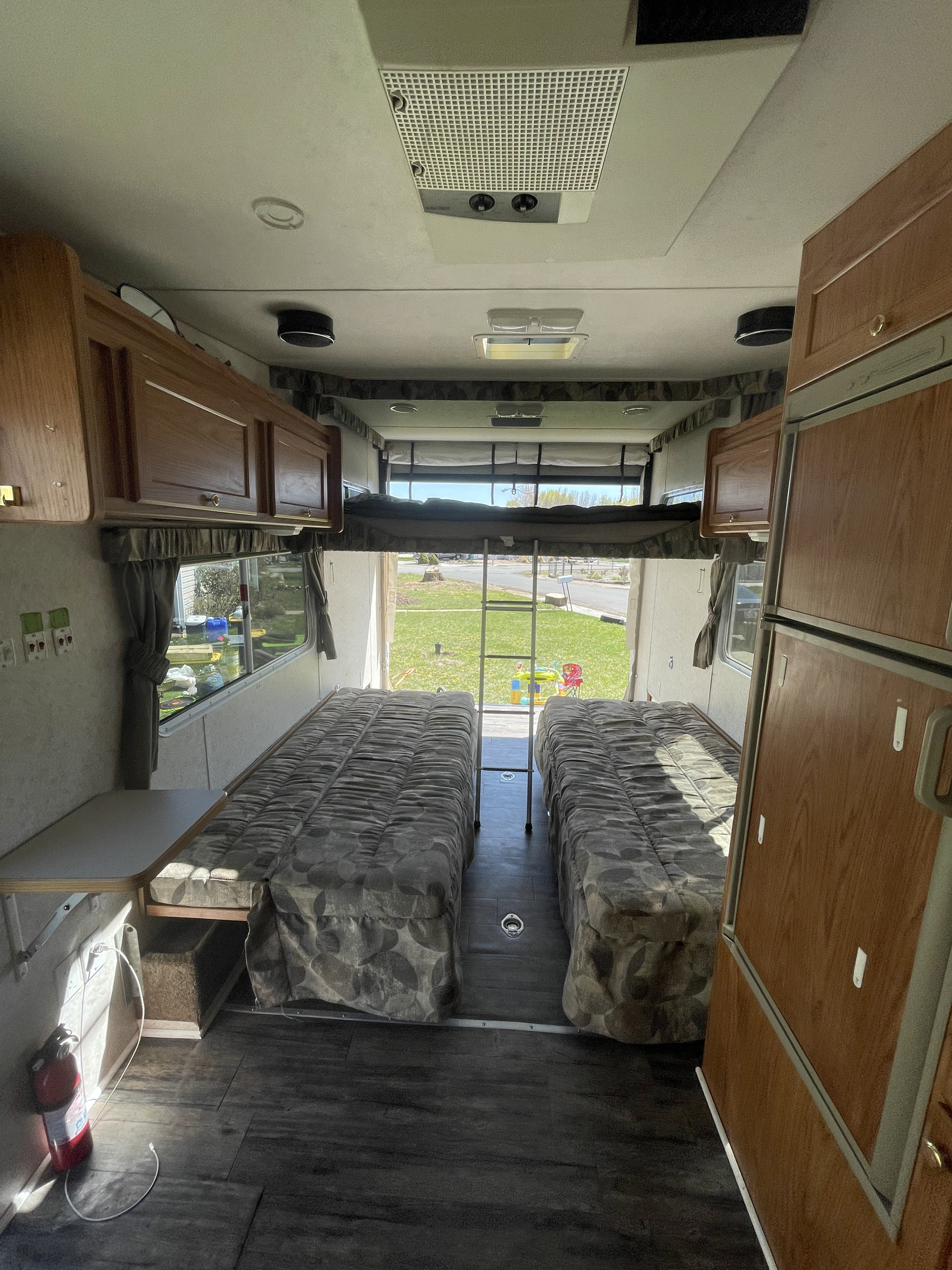 Spacious RV rental interior with two lower beds, an upper bunk, and an open rear ramp overlooking a grassy outdoor area.. Weekend Warrior 1900fk 2005