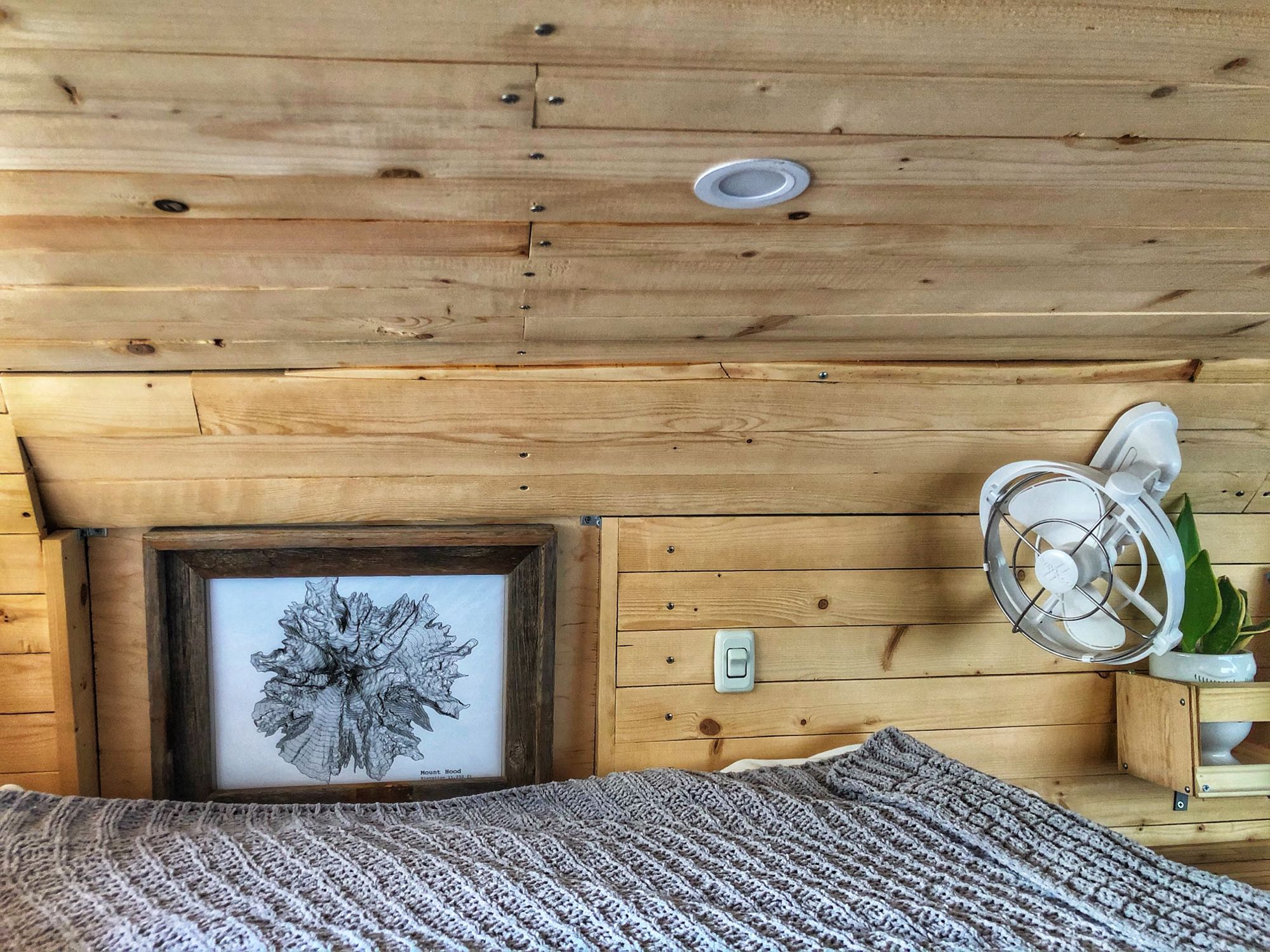 Experience comfort in this RV rental bedroom with wood paneling, a cozy bed, framed art, fan, and plant.. Ford Econoline E250supercab 2006