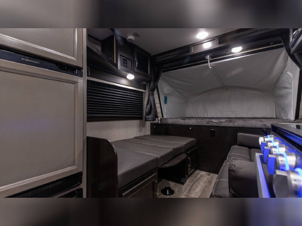 Compact RV rental interior featuring a convertible dinette bed, pop-out sleeping area, kitchen, and refrigerator.. Jayco Jay Feather 2021