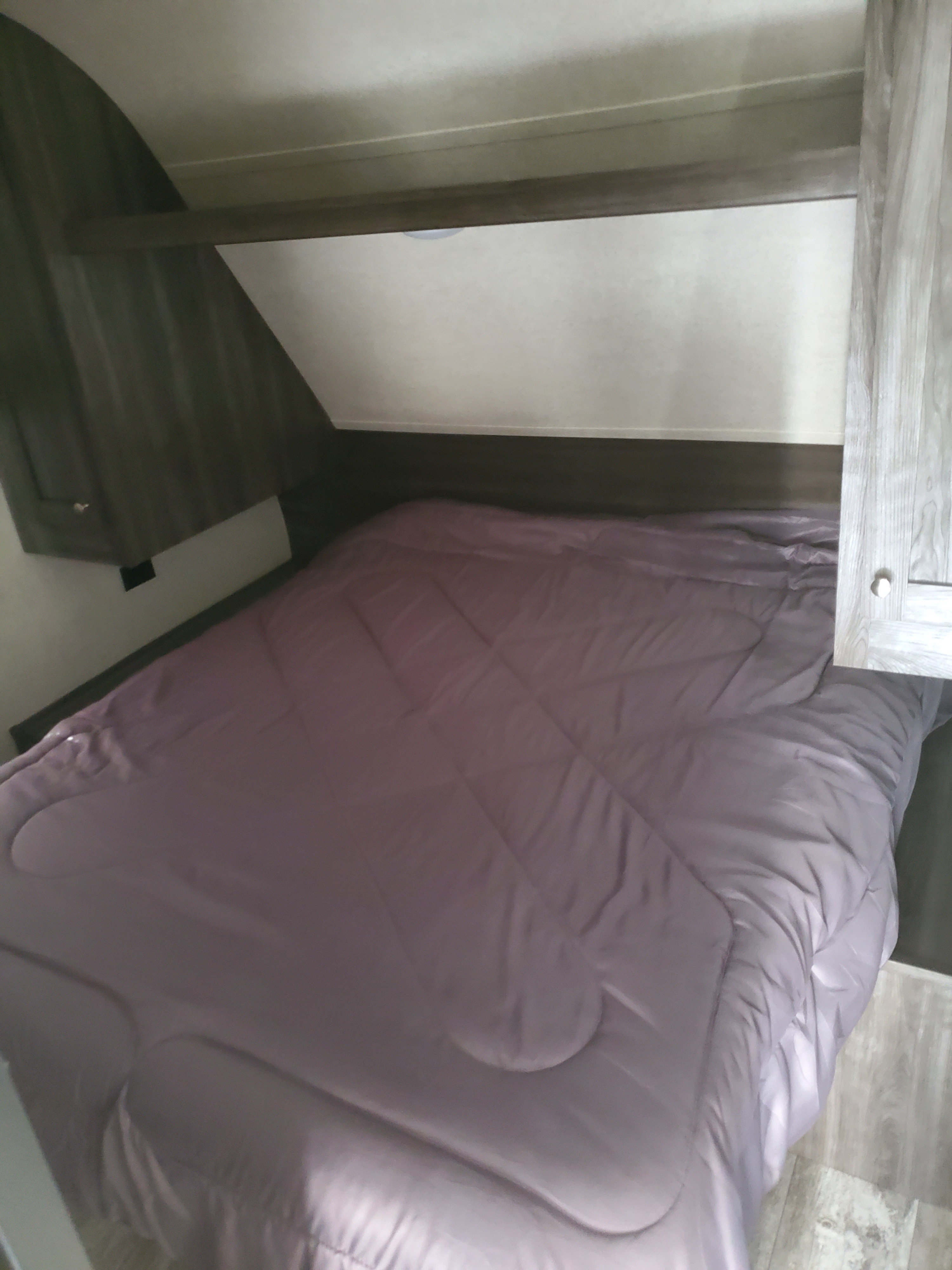 Explore this RV rental bedroom: a cozy bed with purple comforter and storage, ideal for travel accommodation.. Highland Ridge RV Open Range 2019