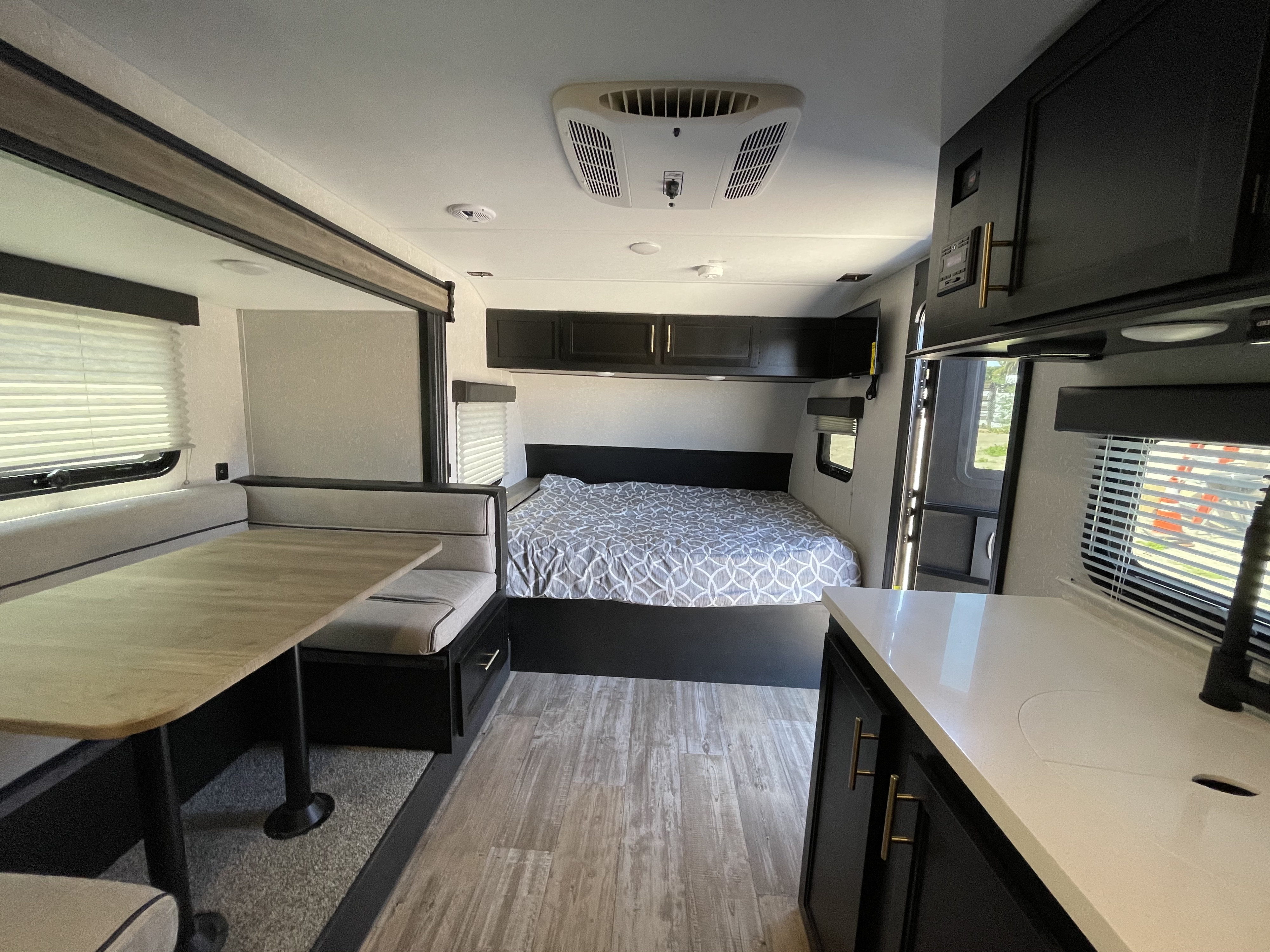 An RV rental's modern interior featuring a cozy bedroom, dinette, and kitchen area.. Forest River Cherokee Wolf Pup 2021