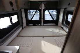 Spacious RV rental interior: Rear view showing two parallel beds, windows, and open back doors of a comfortable camper van.. Winnebago 59P 2021