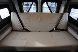 This RV rental features a comfortable, light-colored bench seat that converts to a bed, with visible seatbelts for safe travel.. Winnebago 59P 2021