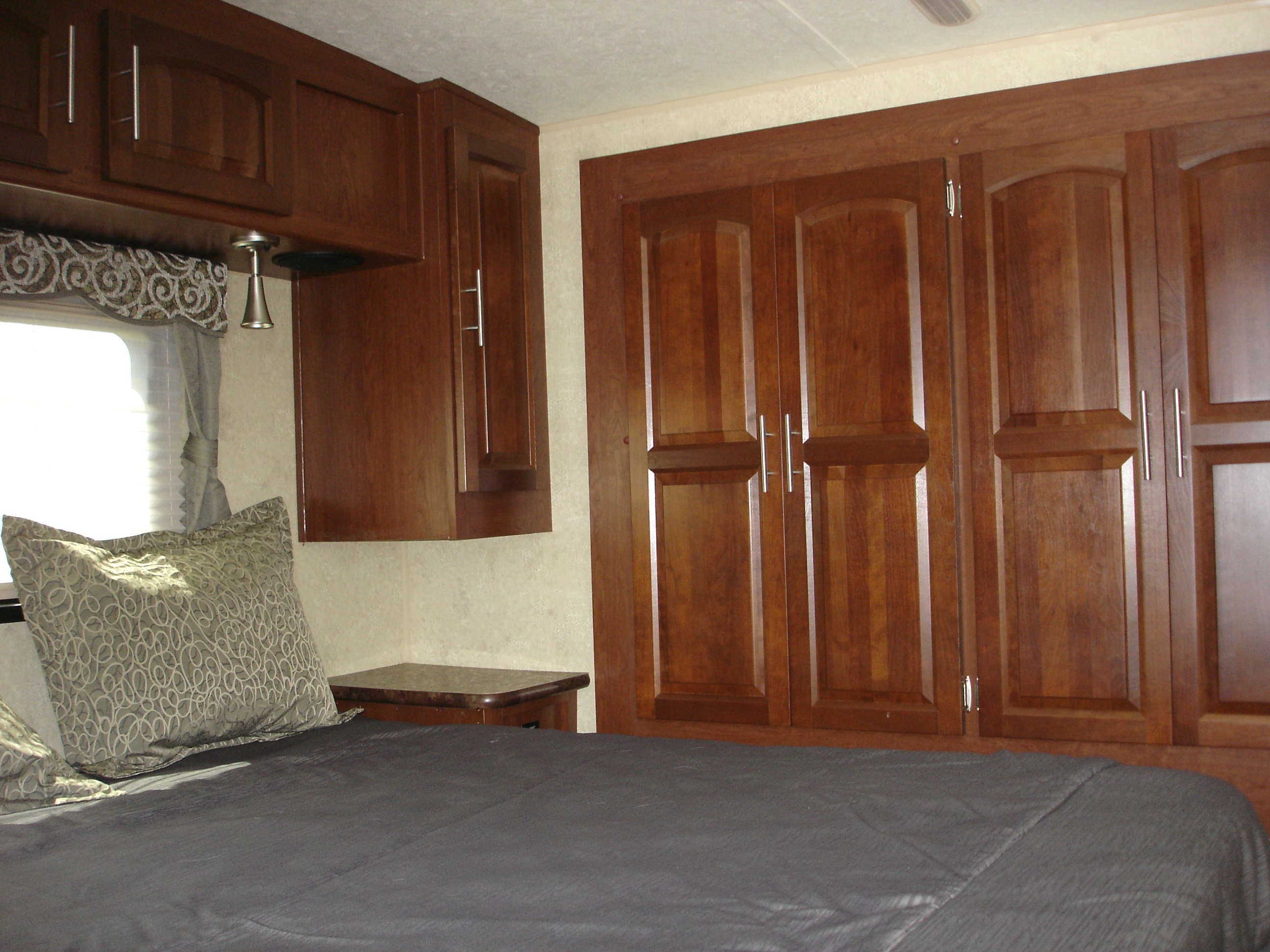 RV rental interior: cozy bedroom with dark wood cabinets, bed, and window. Functional storage & comfort.. Flagstaff 26FKWS Super Lite 2016