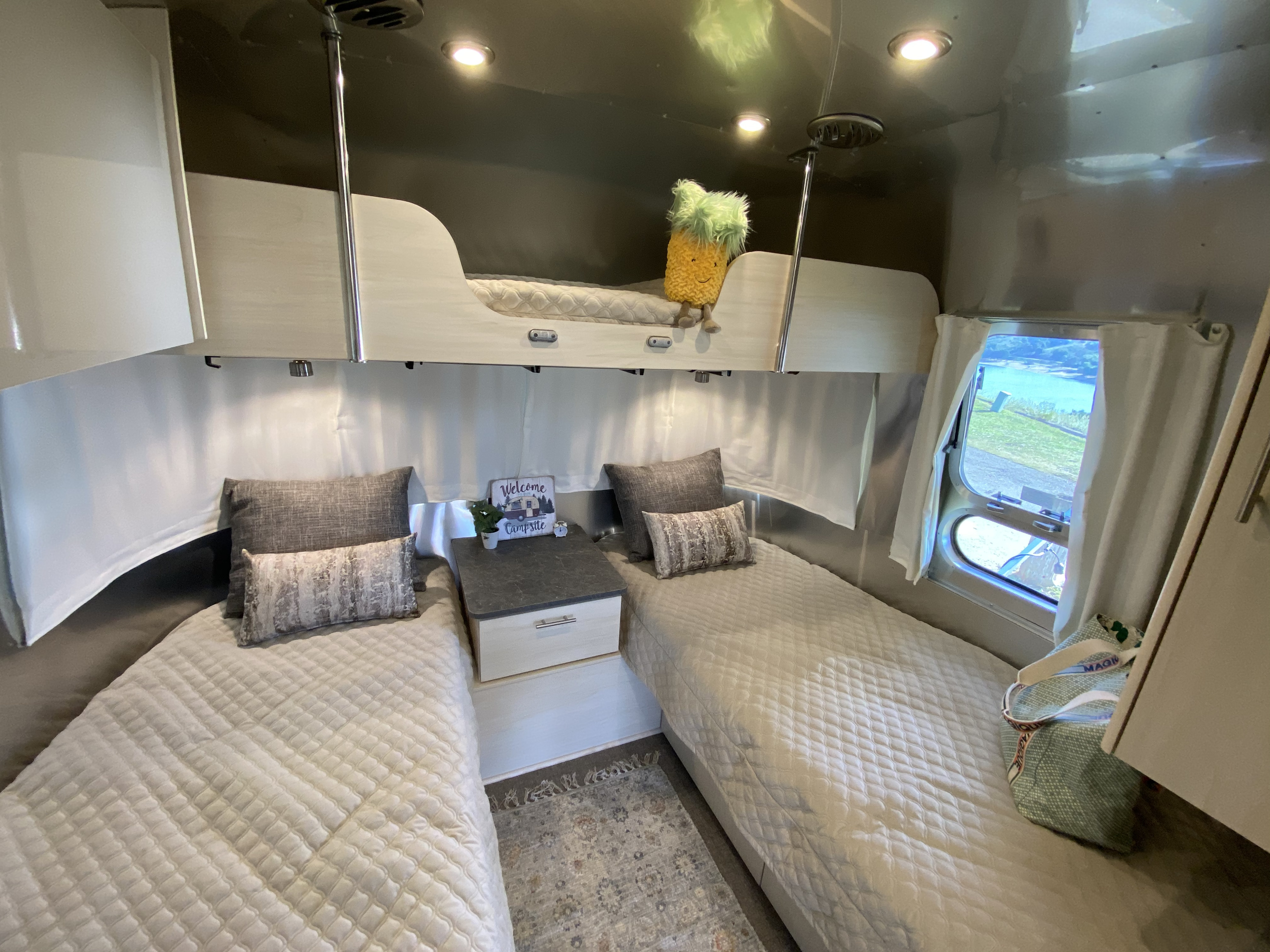 Cozy RV rental bedroom featuring twin beds below, a bunk bed above, and a window view of the outdoors.. Airstream Flying Cloud 2021