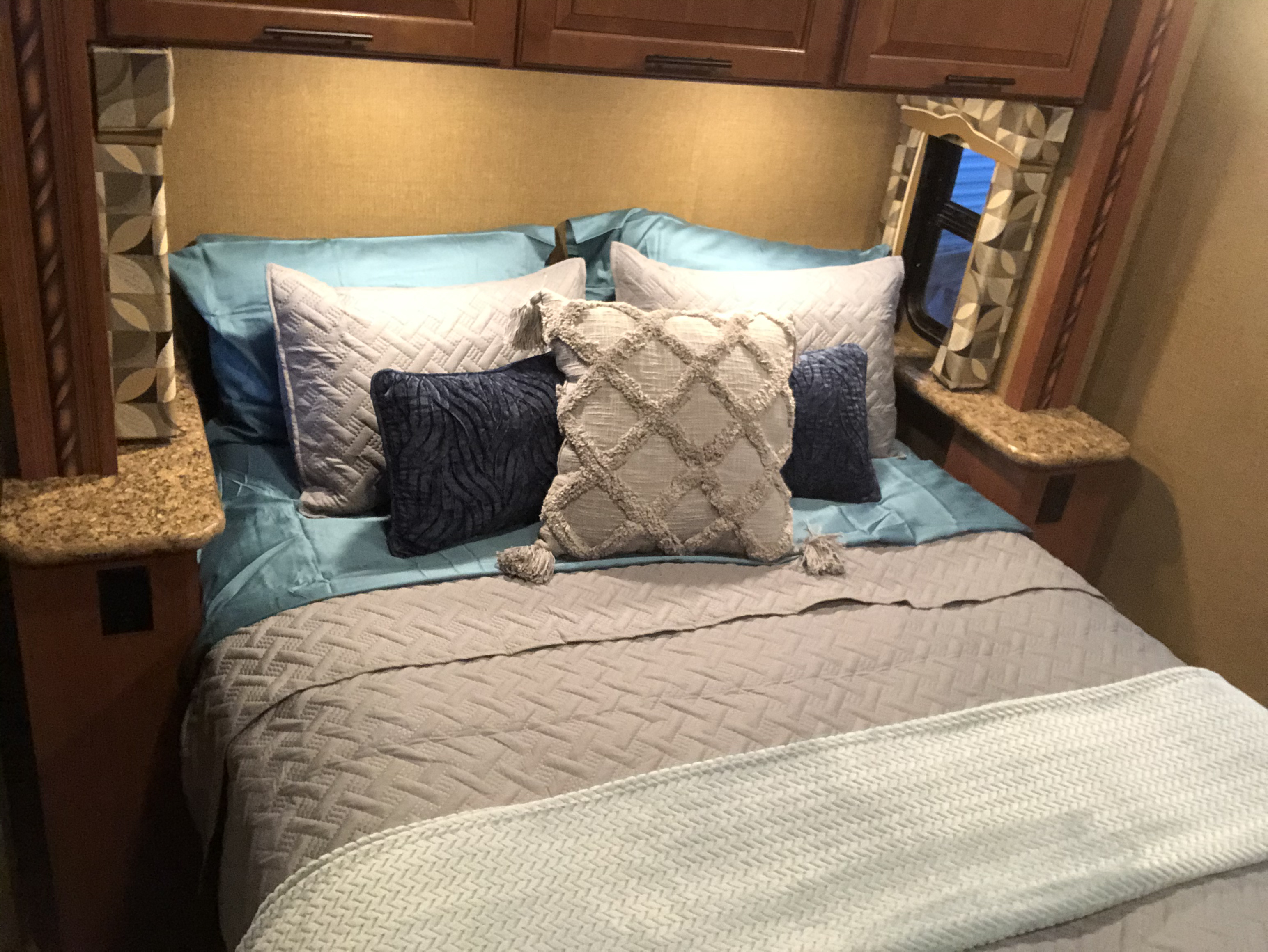 Relax in this inviting RV rental bedroom featuring soft blue and grey bedding, decorative pillows, and storage.. Thor Motor Coach Chateau 2017