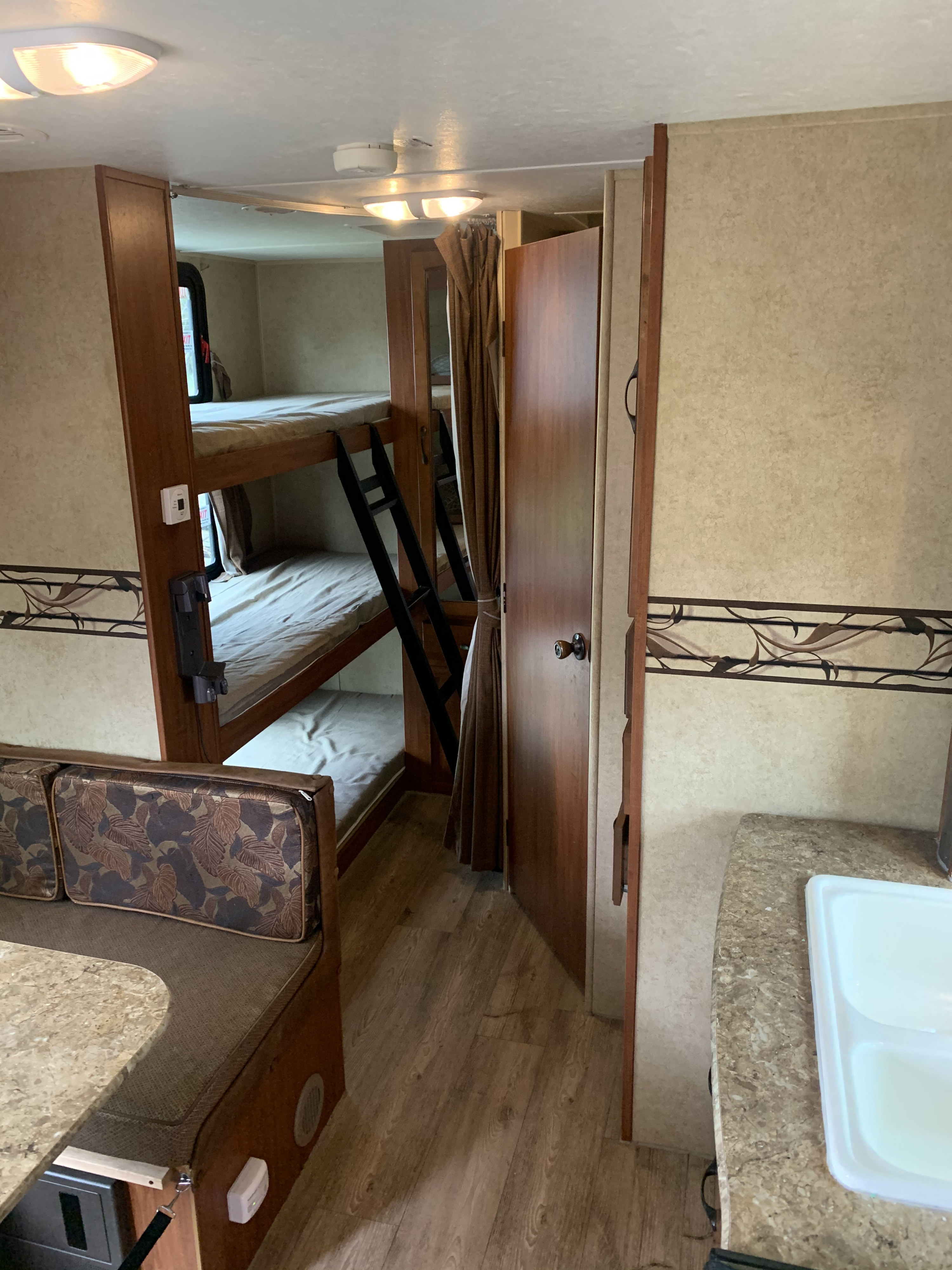 Spacious RV rental interior featuring bunk beds, a cozy dinette, and kitchen area, perfect for family adventures.. Forest River Surveyor Sport 2014