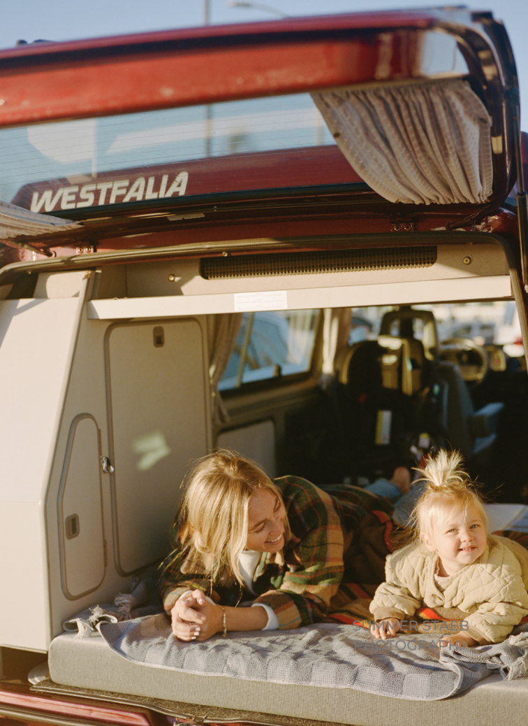 A woman and child happily relax in a Westfalia RV rental, perfect for family travel adventures.. Volkswagen Westfalia 1991