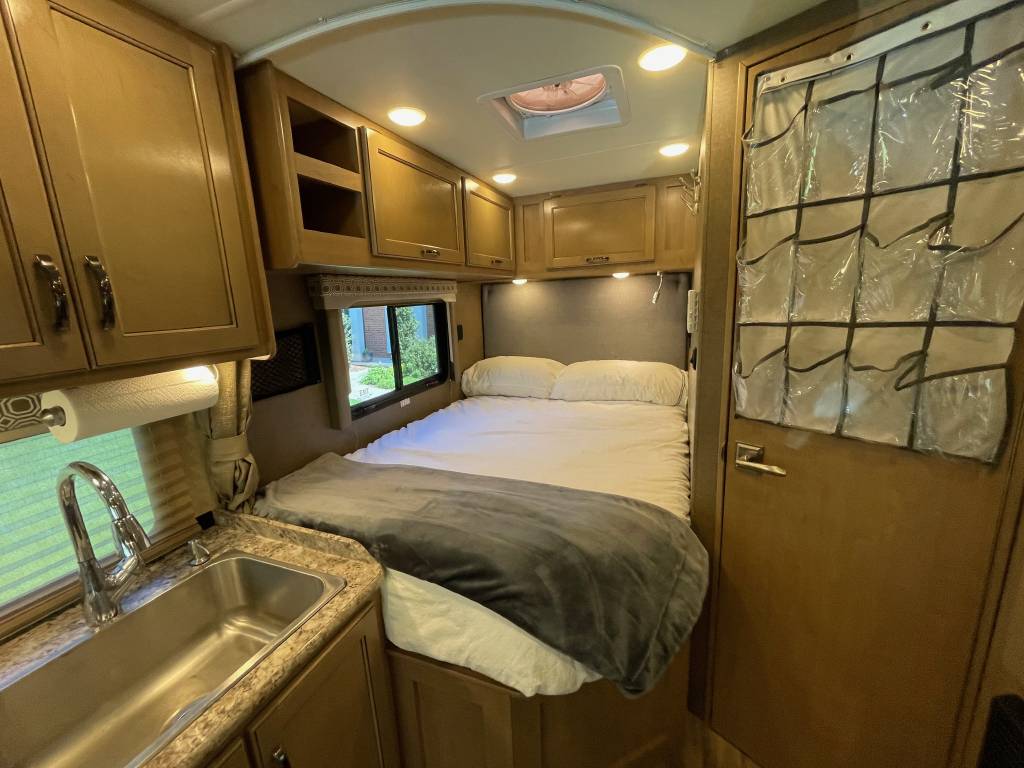 Comfortable RV rental interior with bed, kitchen sink, and ample storage for your mobile adventures.. Thor Motor Coach Four Winds 2019