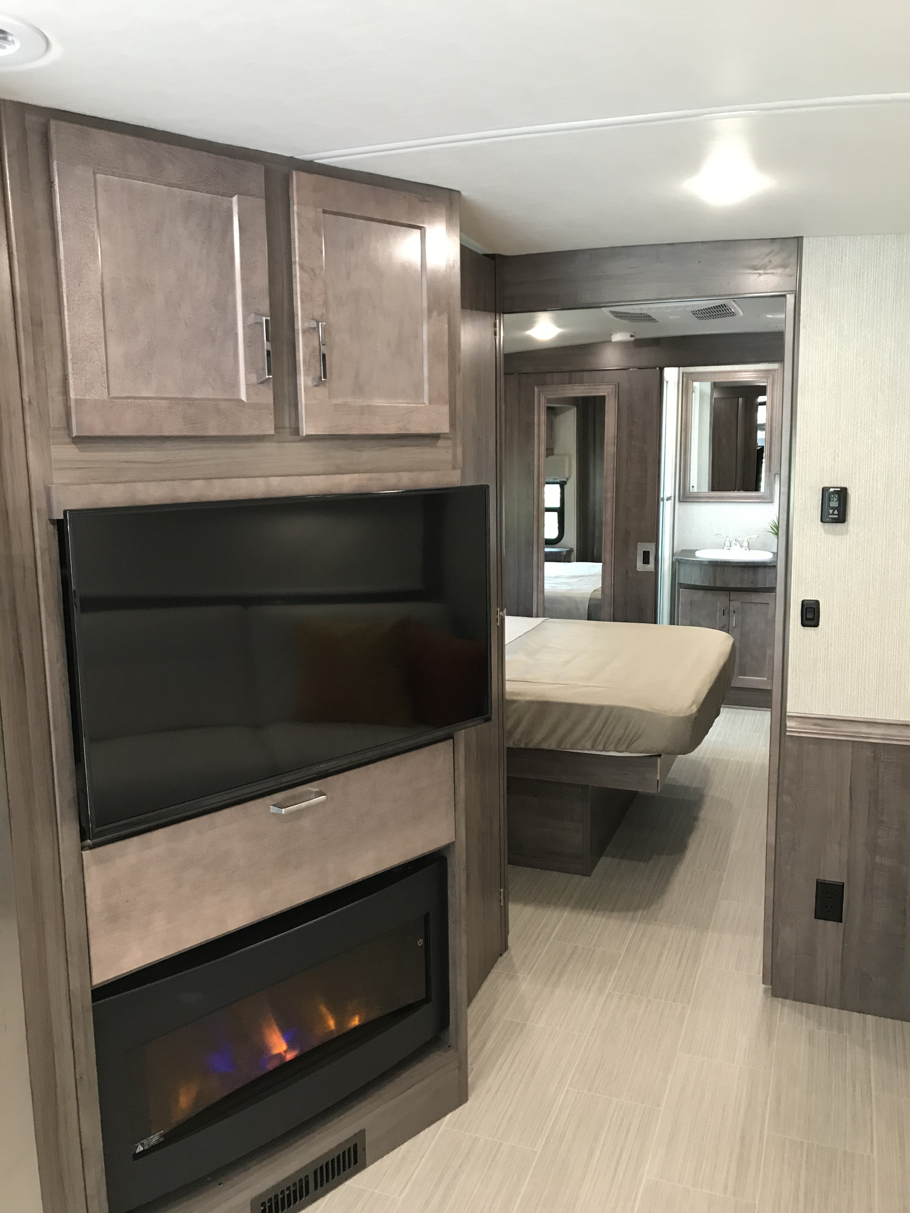 Spacious RV rental interior with a cozy living area, TV, and fireplace, opening to bedroom and bath.. Other Adventurer 2021