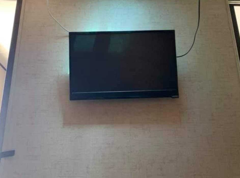 A wall-mounted VIZIO TV, with visible cables, inside an rv rental.. Forest River Surveyor 2016