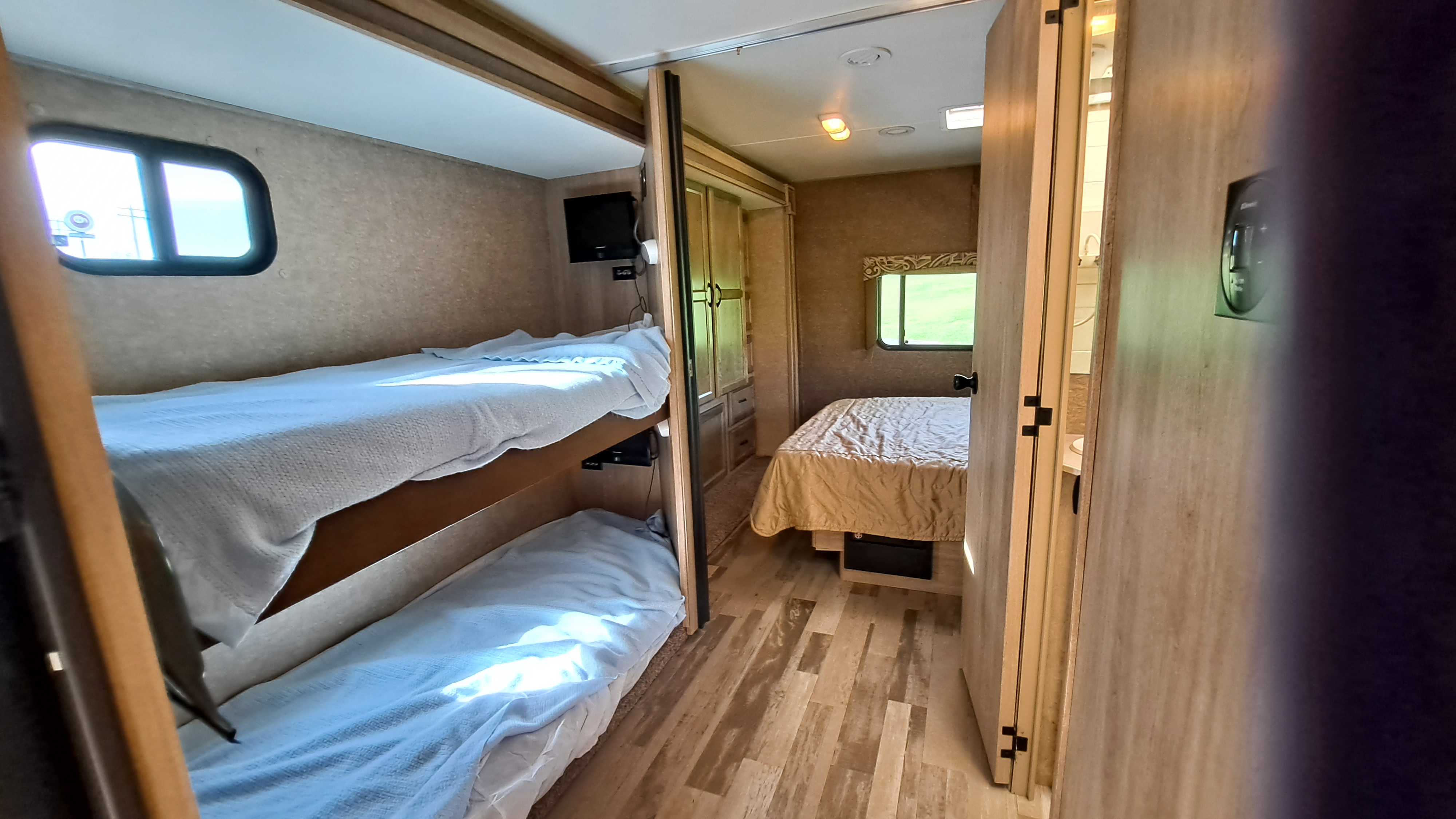Explore this RV rental interior: bunk beds on left, master bedroom straight ahead, and bathroom access on the right.. Coachmen Freelander 2015