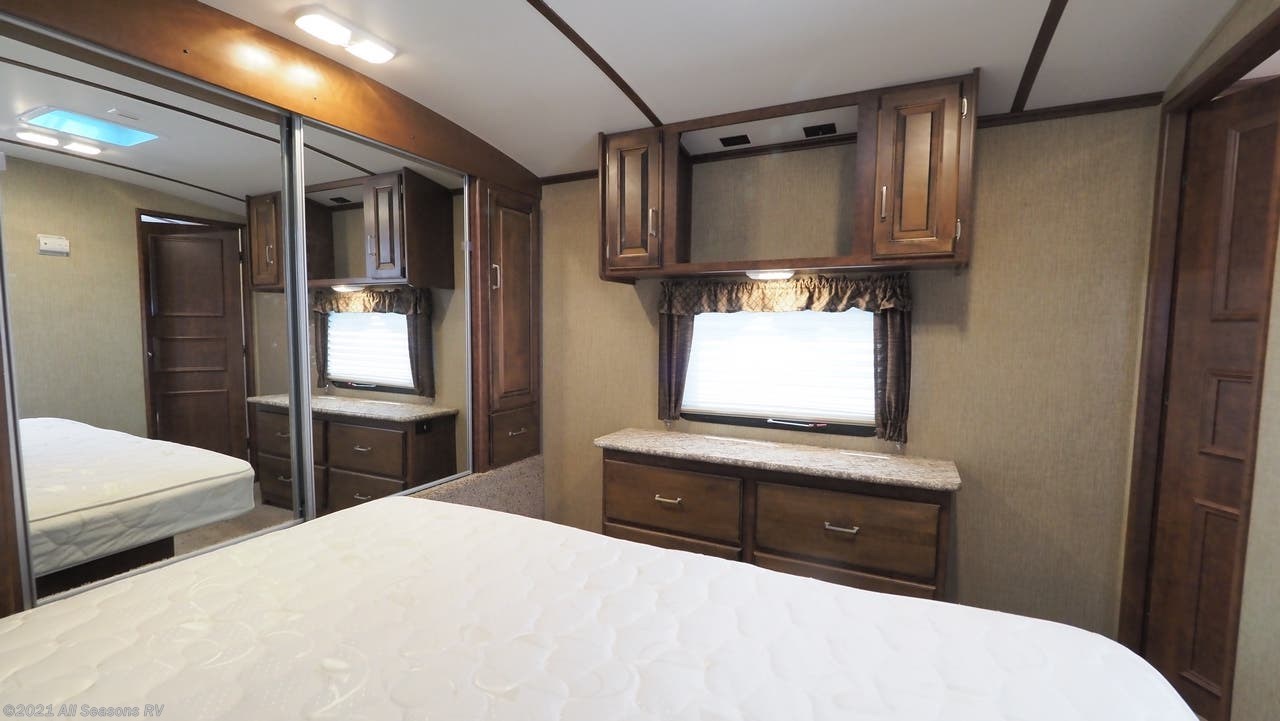 Spacious RV rental bedroom with a large bed, mirrored closet, and built-in storage cabinets. Ideal for comfortable travel.. Keystone Outback 2016