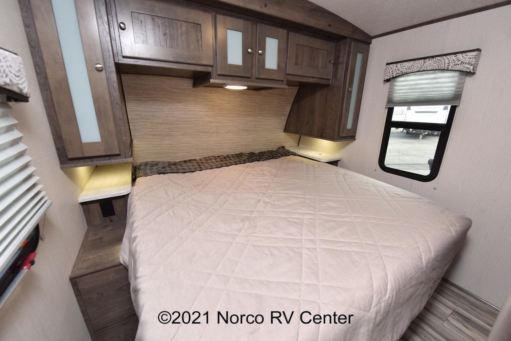 Inside an RV rental, a comfy bedroom features a queen bed, overhead cabinets, and bedside shelving with reading lights.. Cruiser Rv Corp mpg 2016