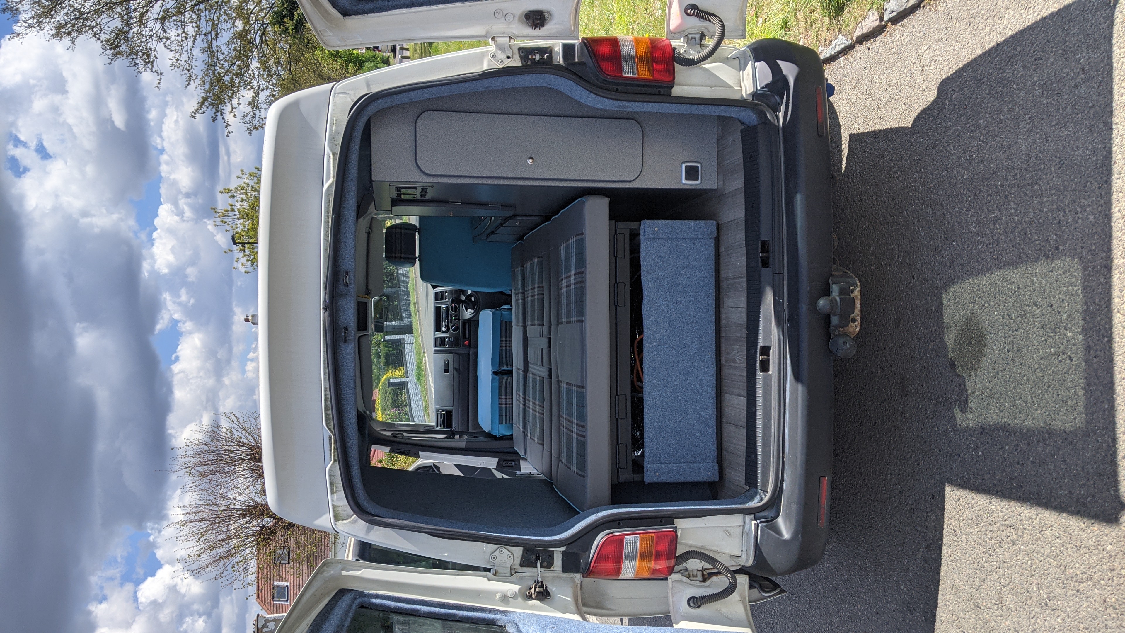 Rear view of an RV rental camper van interior. Features a bed, custom storage, and blue upholstery, highlighting the conversion.. vw T5 2004