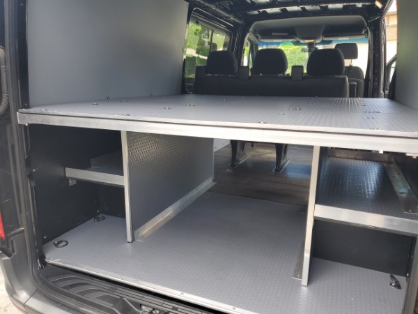 Spacious RV rental interior with an elevated bed platform and organized storage compartments for gear and supplies.. Freightliner Sprinter 2019