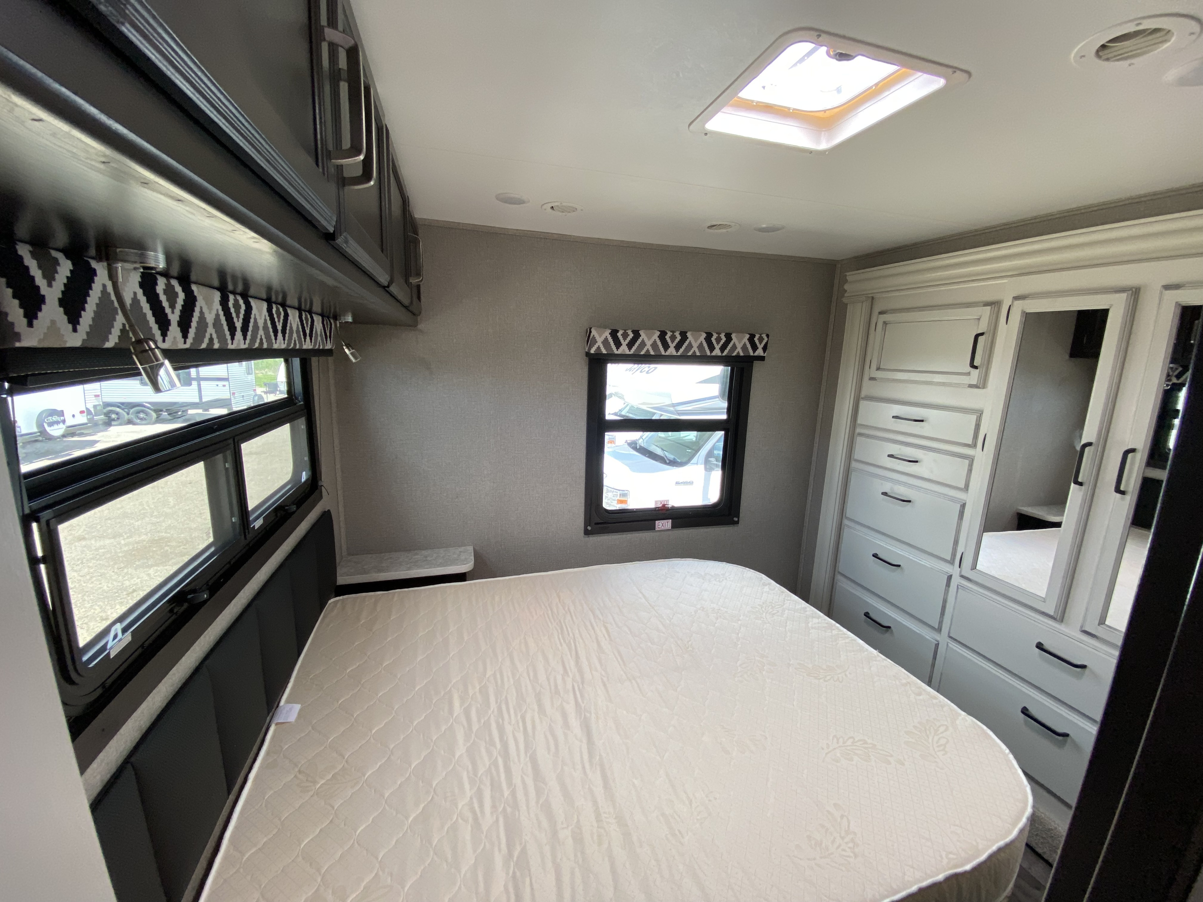 Spacious RV rental bedroom with a comfortable mattress, ample storage, windows, and a skylight for natural light.. Jayco Redhawk 2025