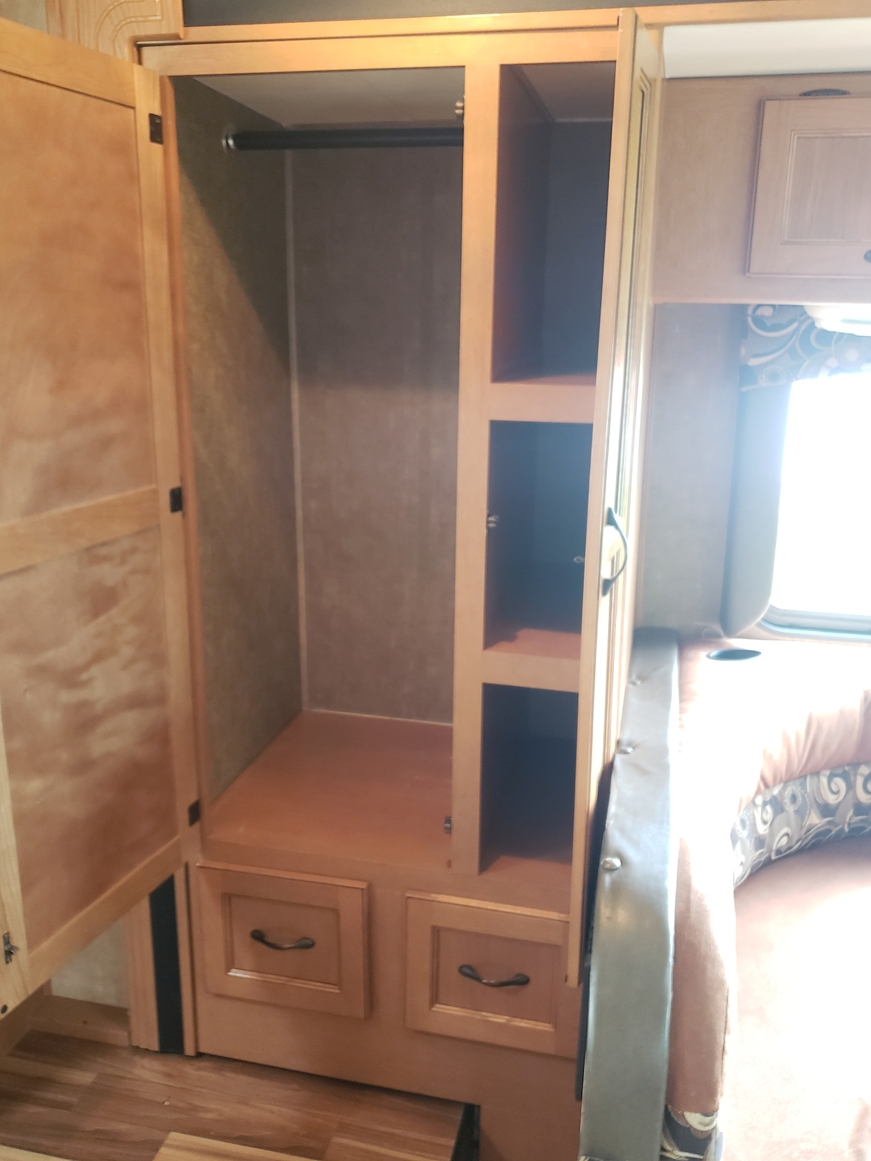 RV rental: Open light-wood wardrobe with hanging rod, shelves, and drawers, offering ample storage in an RV interior.. Coachmen Freelander 2013