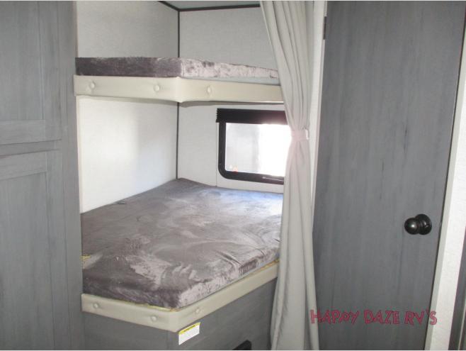 RV rental bunk beds provide comfortable sleeping for family trips. Features two beds, a window, and privacy curtain in this RV interior.. Dutchmen Colorado 2021