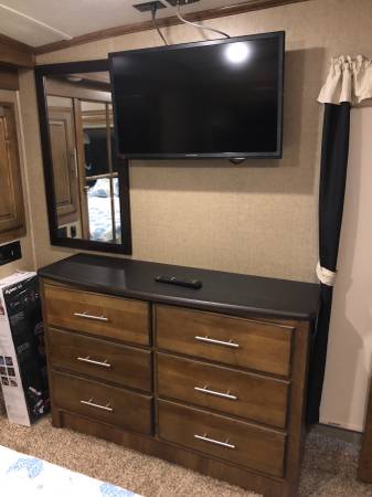 This cozy RV rental bedroom features a wall-mounted TV, spacious dresser for storage, and a large mirror.. Coachmen Brookstone 2015