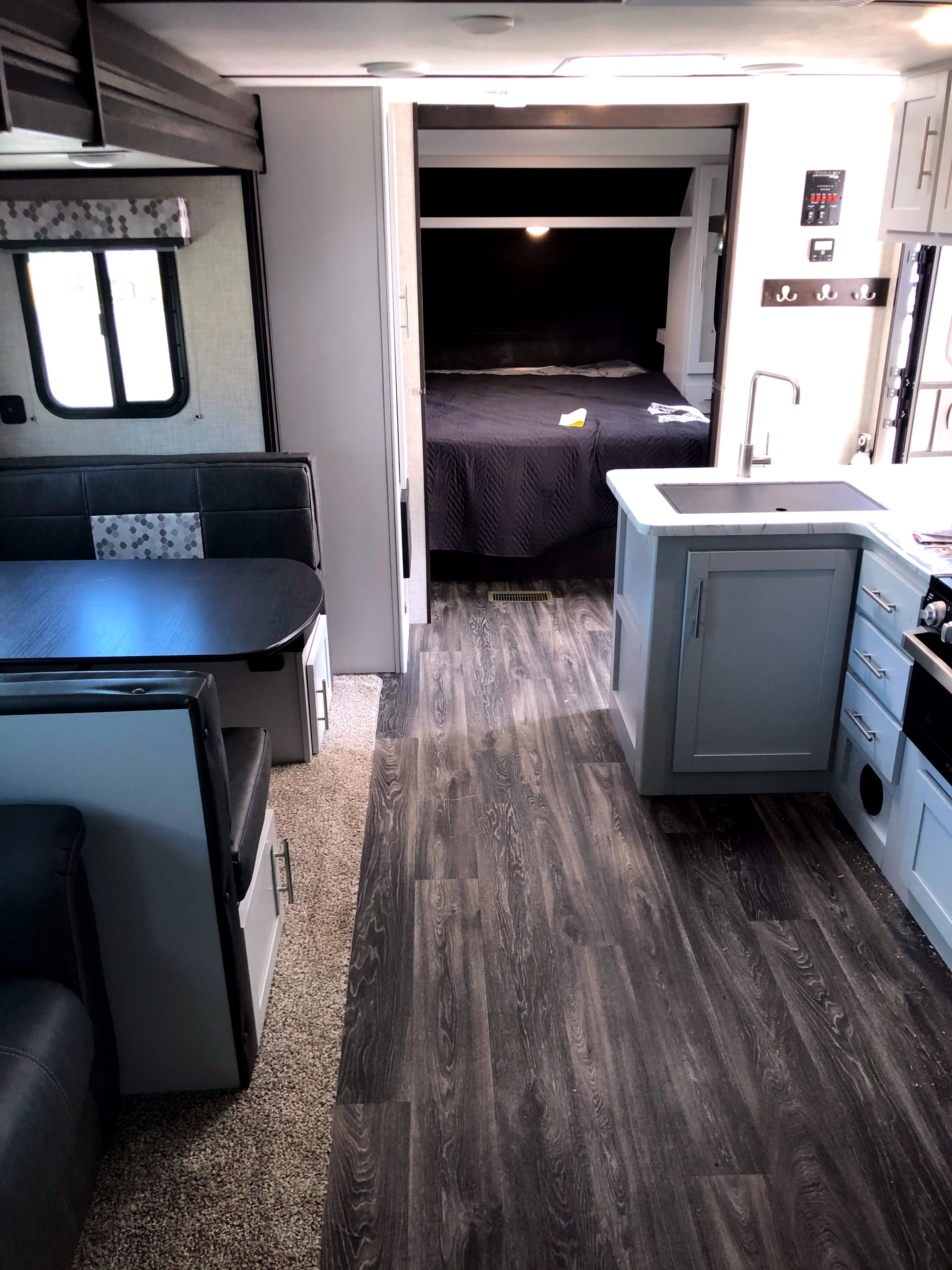 Interior of an RV rental showing the integrated living space: dinette, kitchen, and private bedroom beyond.. Keystone Bullet 2020