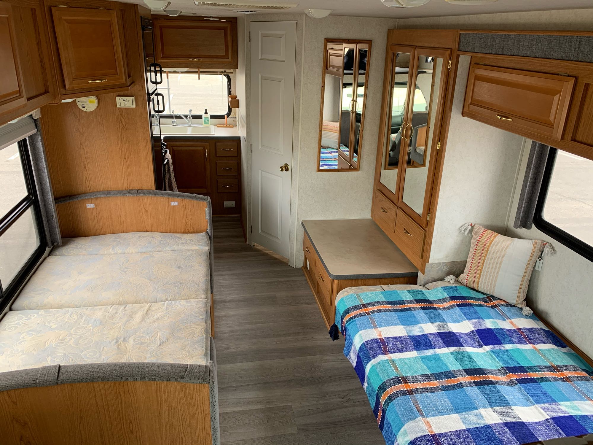 RV rental interior view with two sleeping areas, compact kitchen, and built-in storage. Ideal for road trips!. Fleetwood Tioga 2003