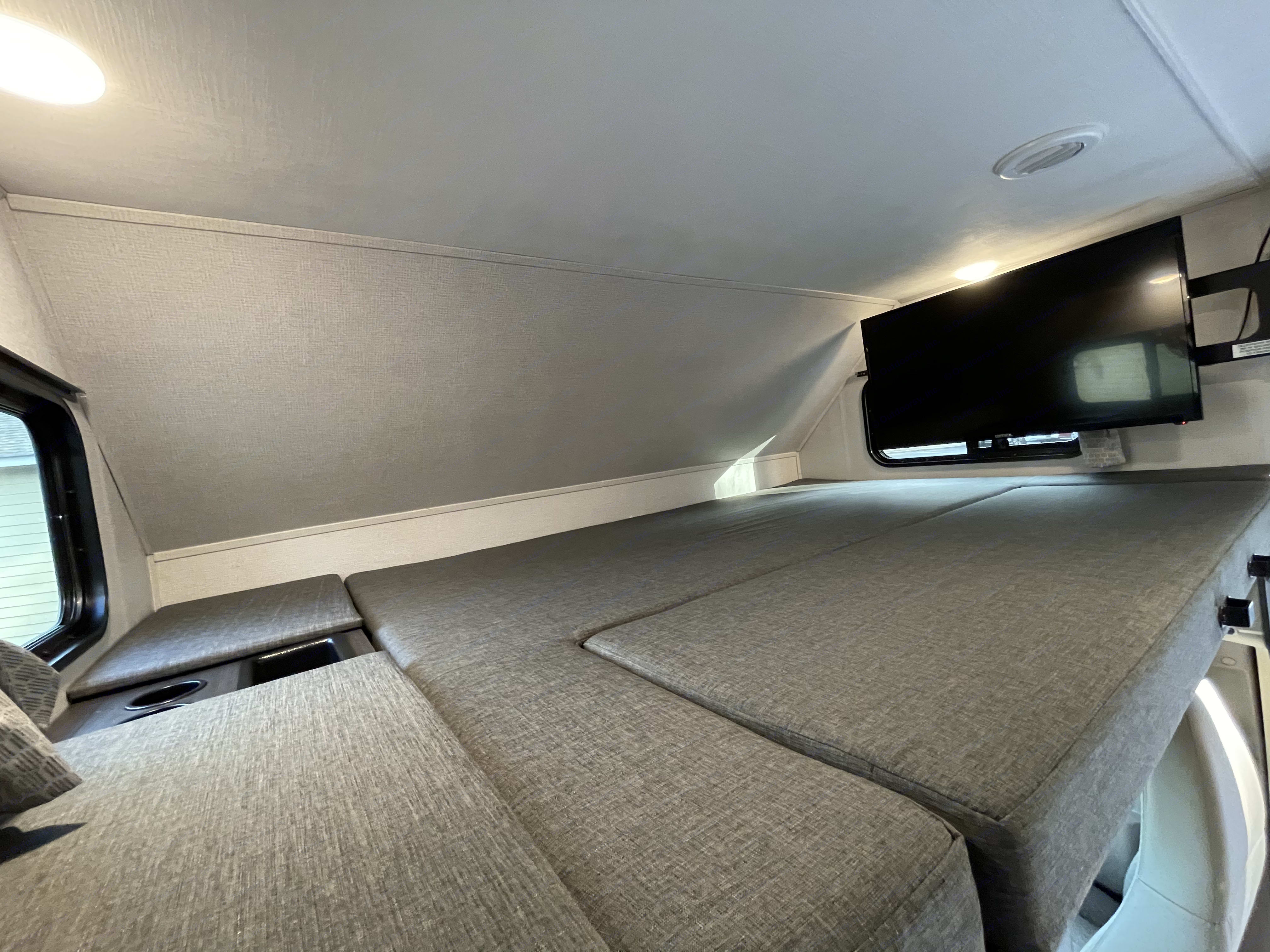 Cozy RV rental bunk bed with a mounted TV and convenient cup holders, ideal for comfortable travel.. Forest River Forester 2021