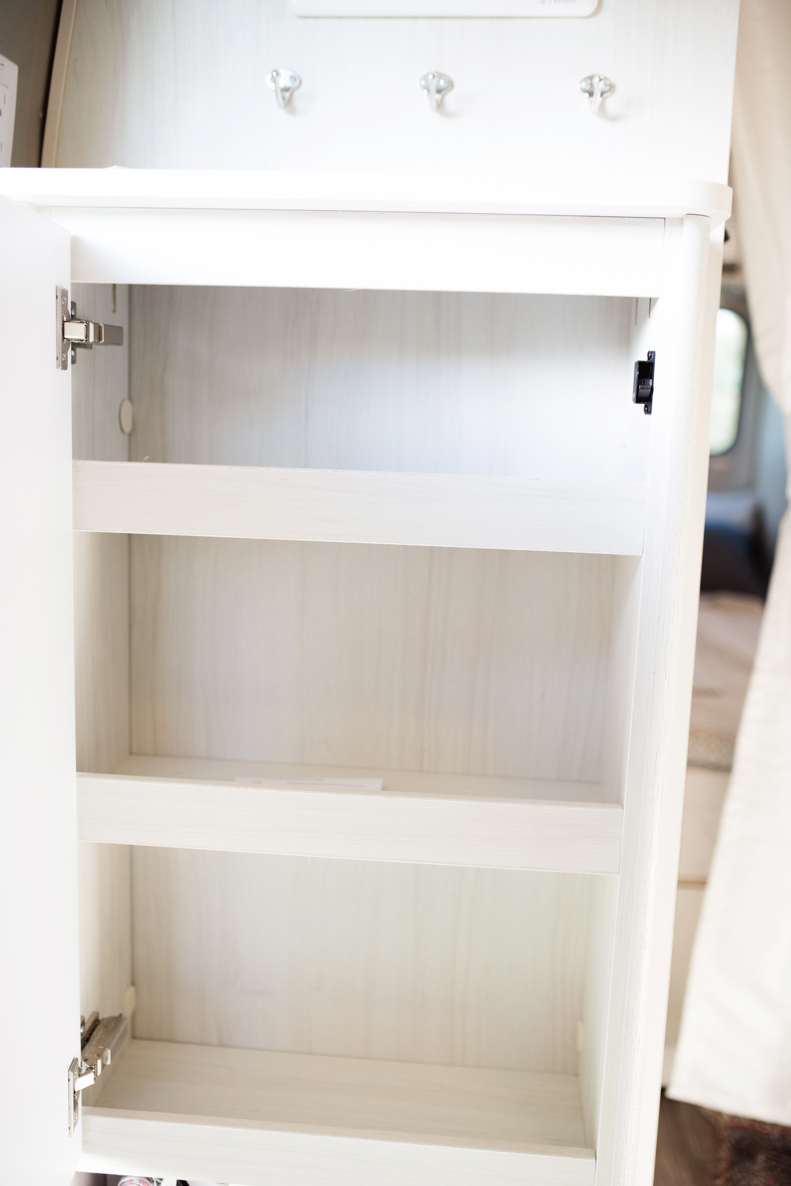 Compact RV rental: open white cabinet with empty shelves, ready for storage.. Airstream Bambi 2021