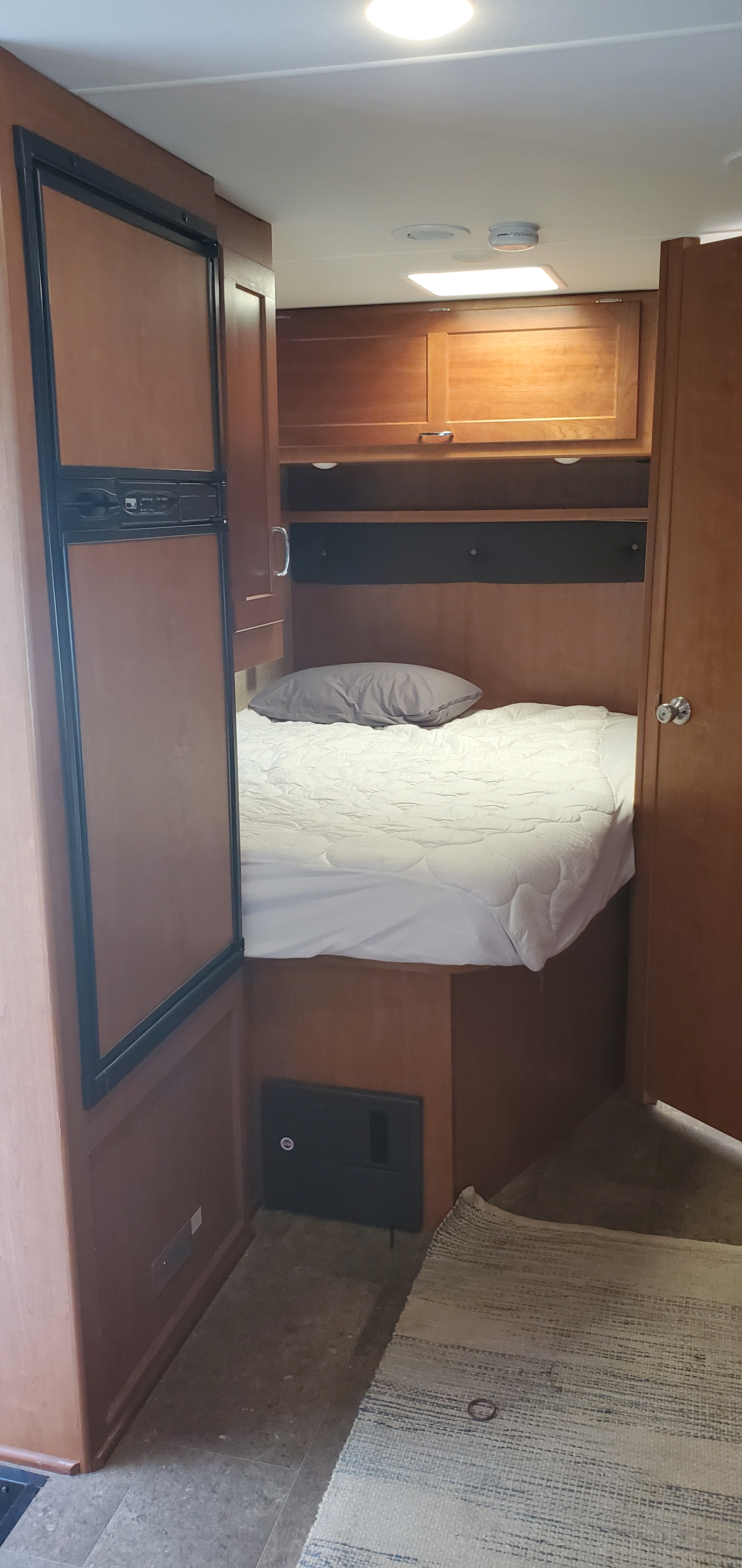 RV rental bedroom: compact space with bed, mini-fridge, and overhead storage, perfect for travel.. Winnebago Minnie Winnie 2017