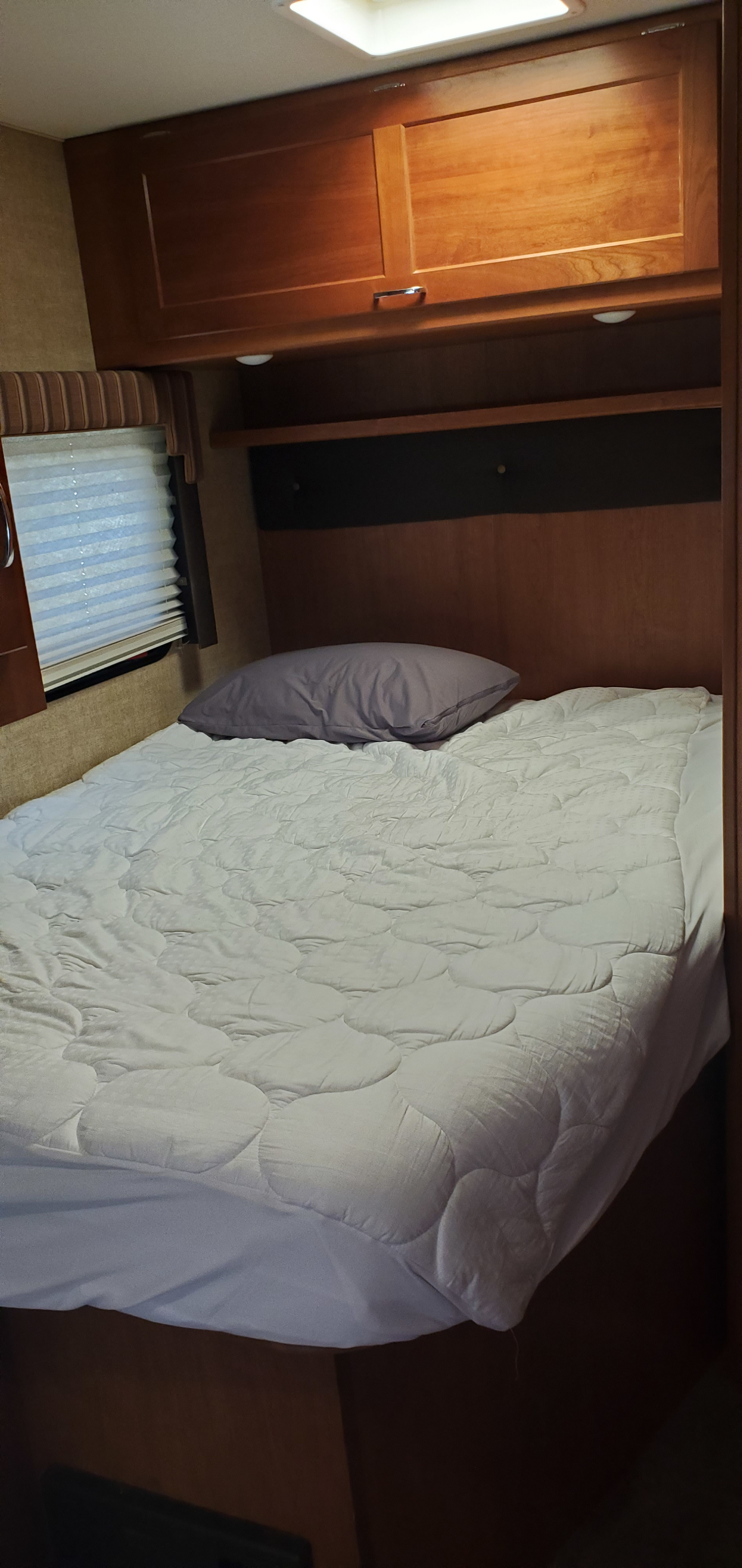 Cozy RV rental bedroom with comfortable bed, cabinets, and window.. Winnebago Minnie Winnie 2017